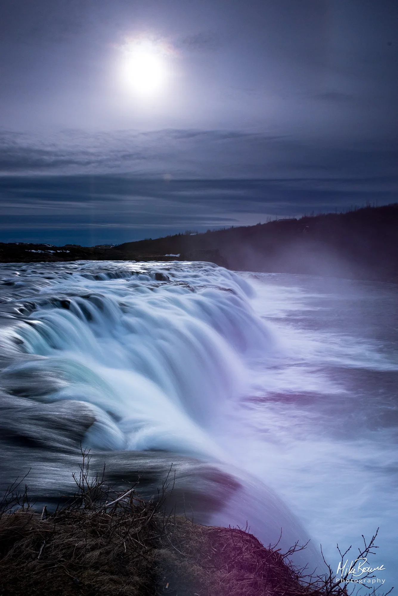 waterfall in Iceland with moon in sky above