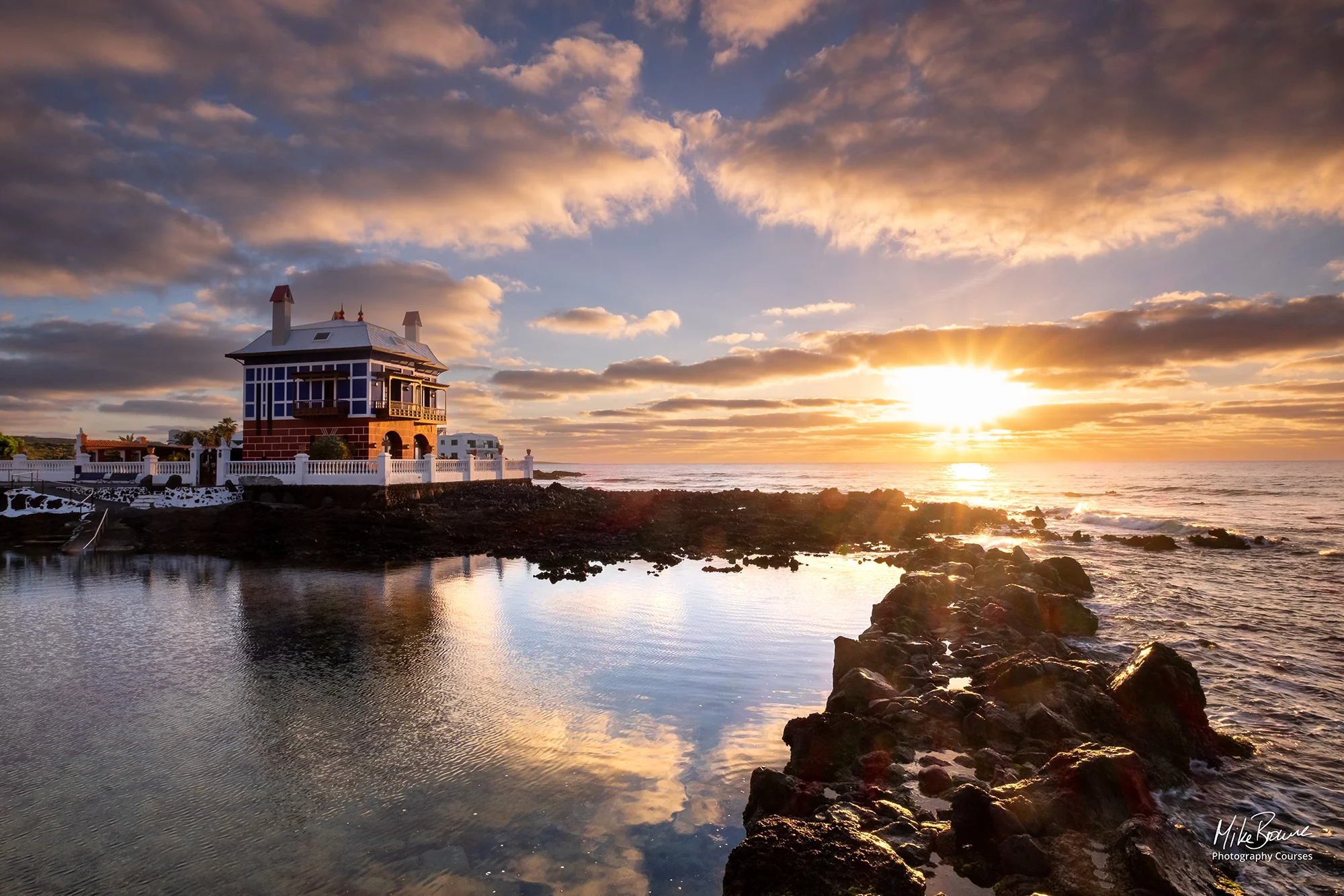 Red brick house by a tidal pool at sunrise
