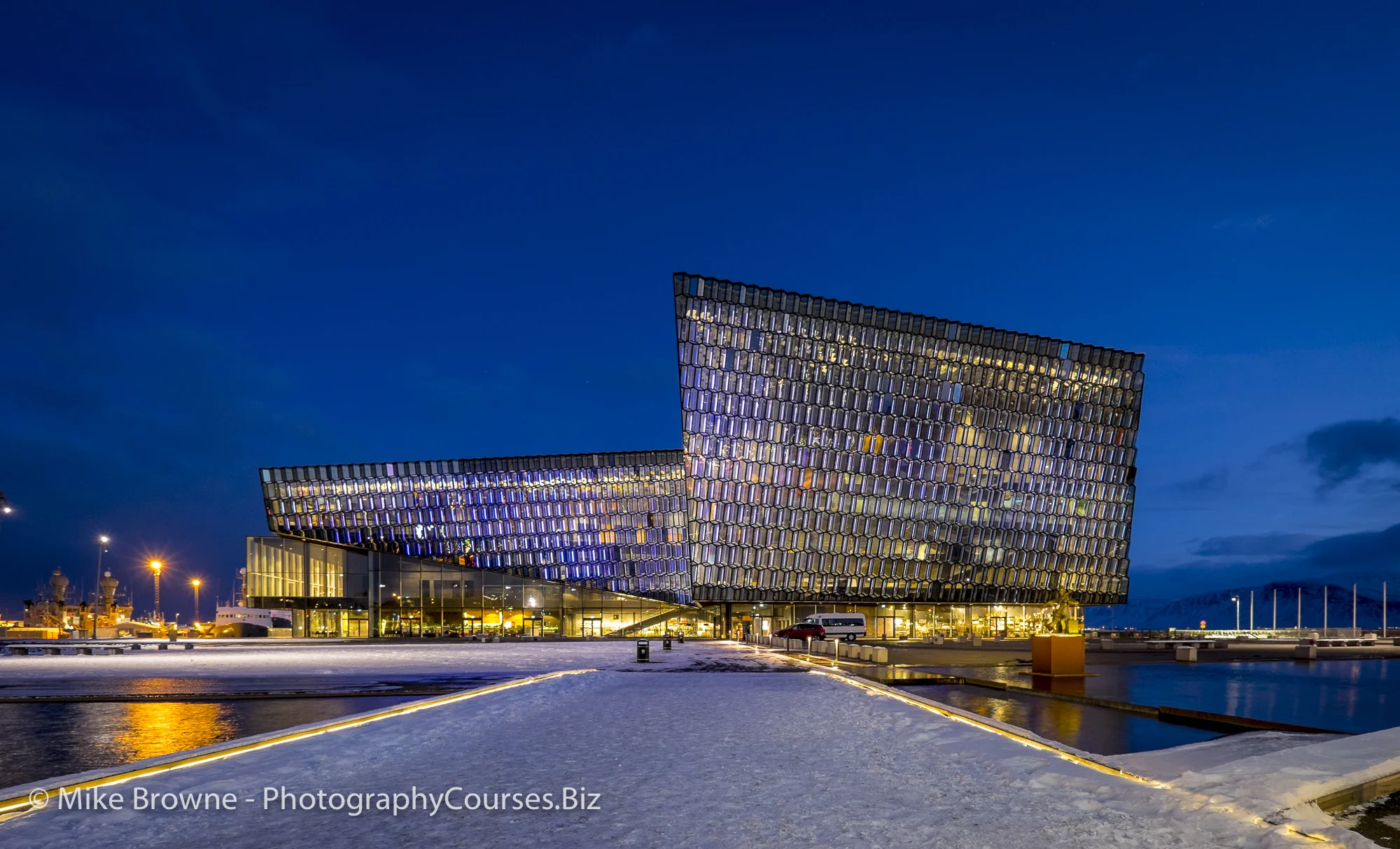 Modern glass building at twilight blue hour with snow covered path