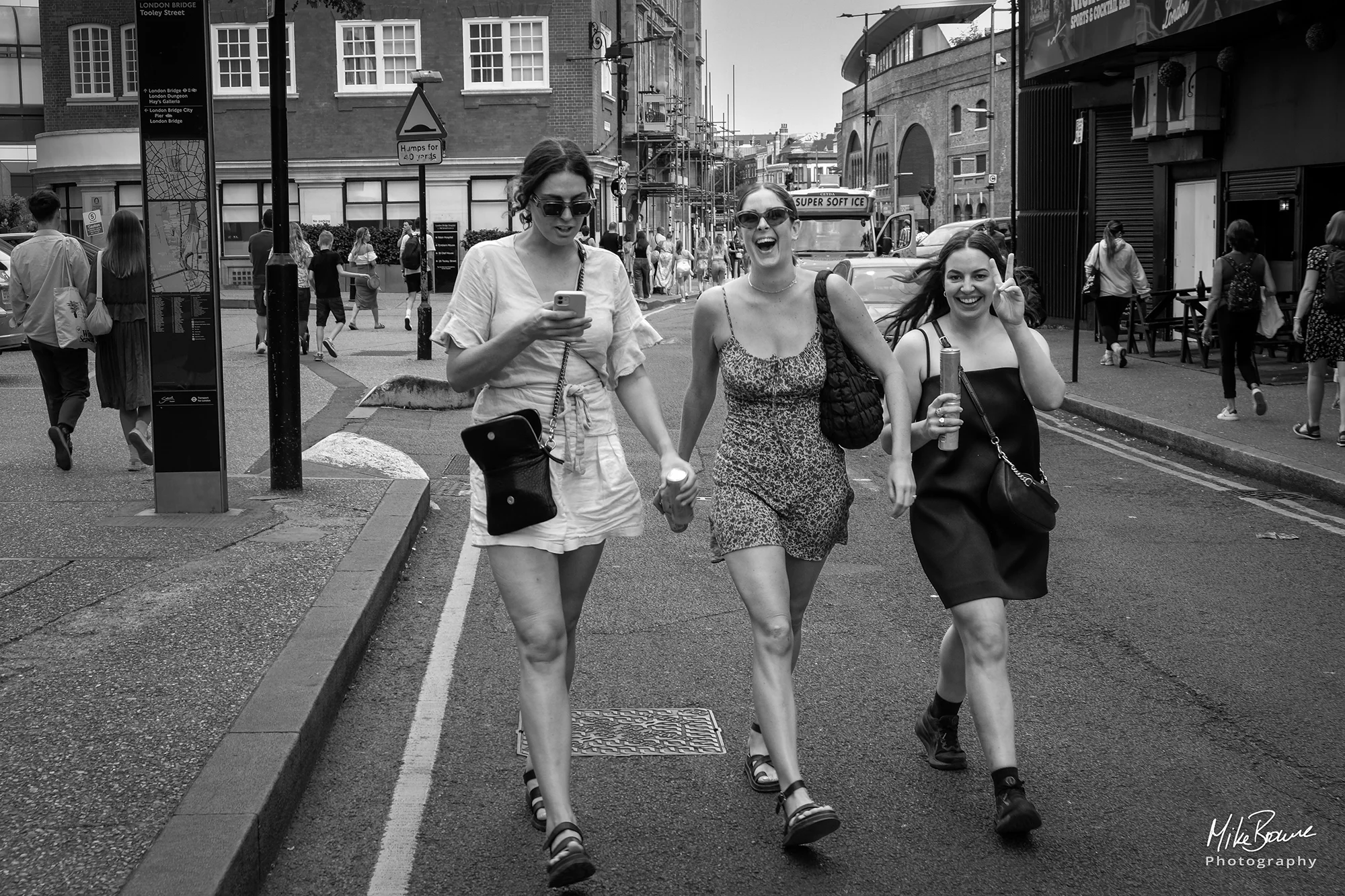 Three young women wearing sunglasses striding along a London street