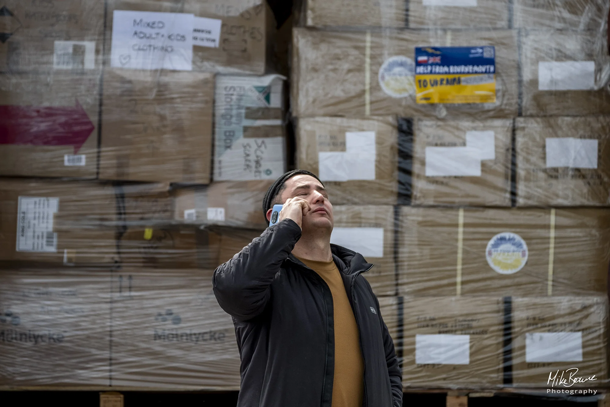 Man in front of aid to Ukraine with a pained expression holding phone to his ear
