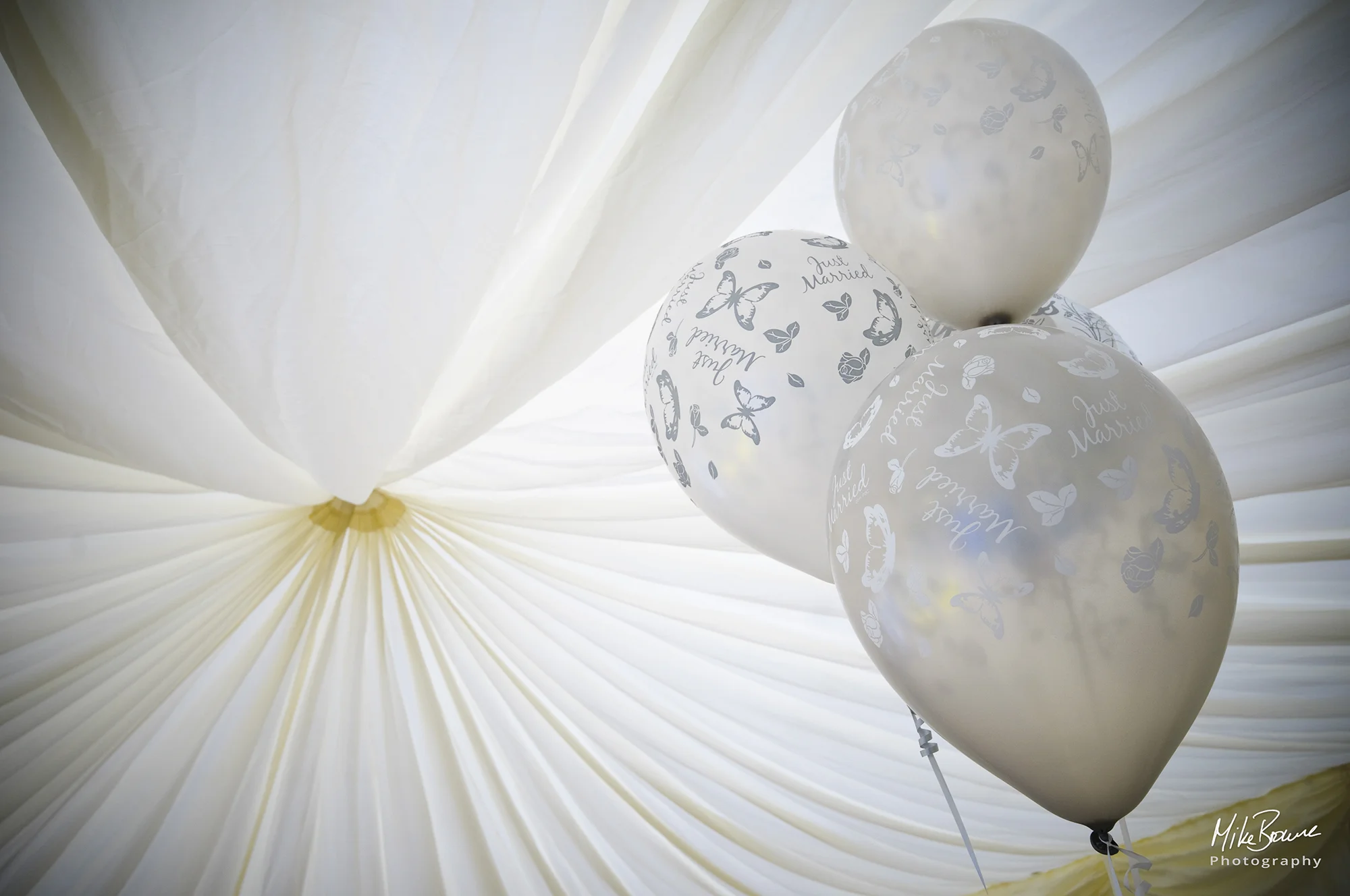 Three white balloons with silver stars in a marquee