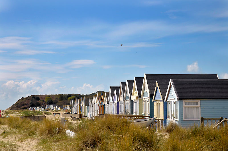Parade of beach huts with Hengistbury Head hill in the background