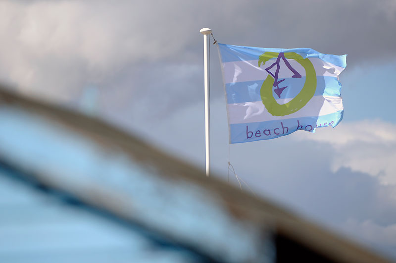 A single Beach House cafe flag blowing in front of clouds