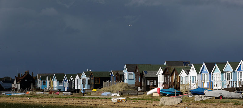 Beach huts on Mudeford spit with a dark and ominous sky