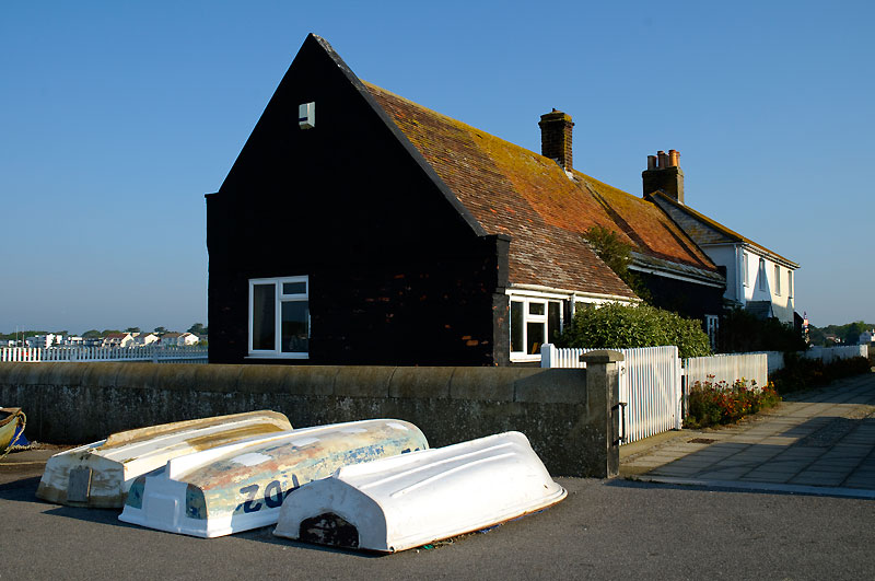 House in Mudeford Quay conservation area with three upturned skiffs outside