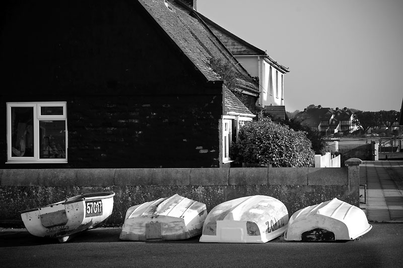 Three upturned boats and one the right way up in front of house at Mudeford Quay