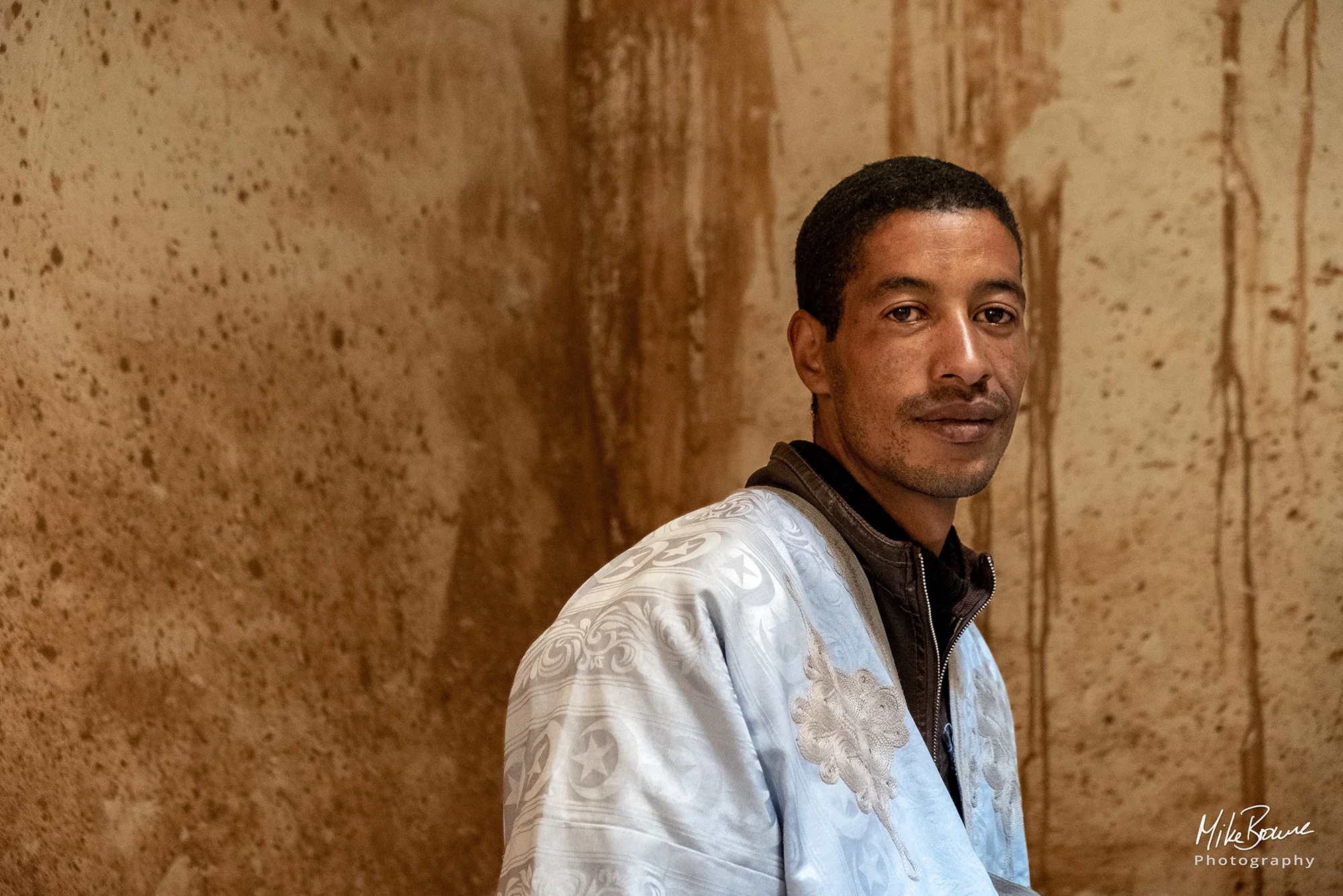 Young man wearing a grey djellaba in a Kasbah in Morocco