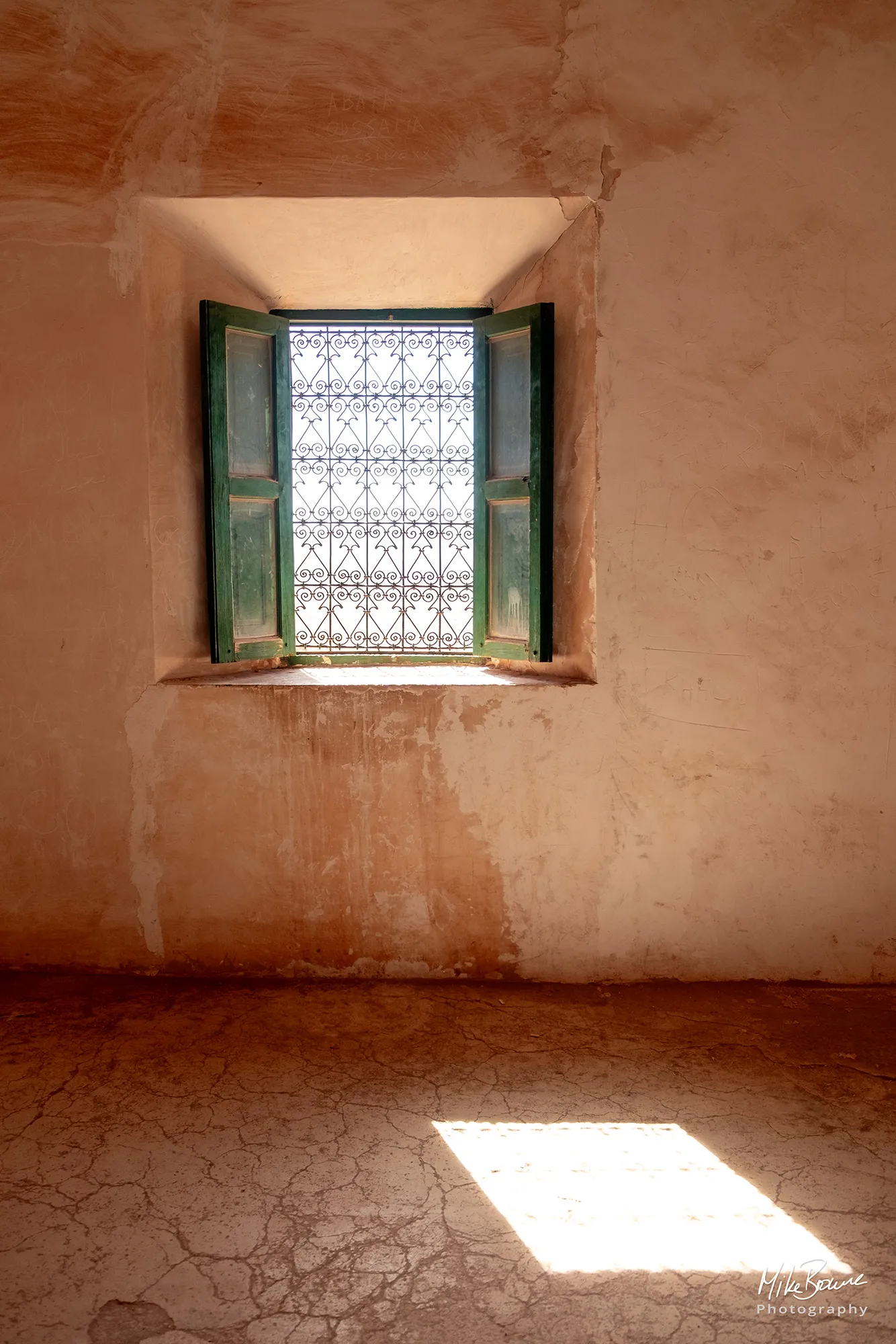 A bright sunny window with green shutters and sun shining on the floor at a Moroccan Kasbah