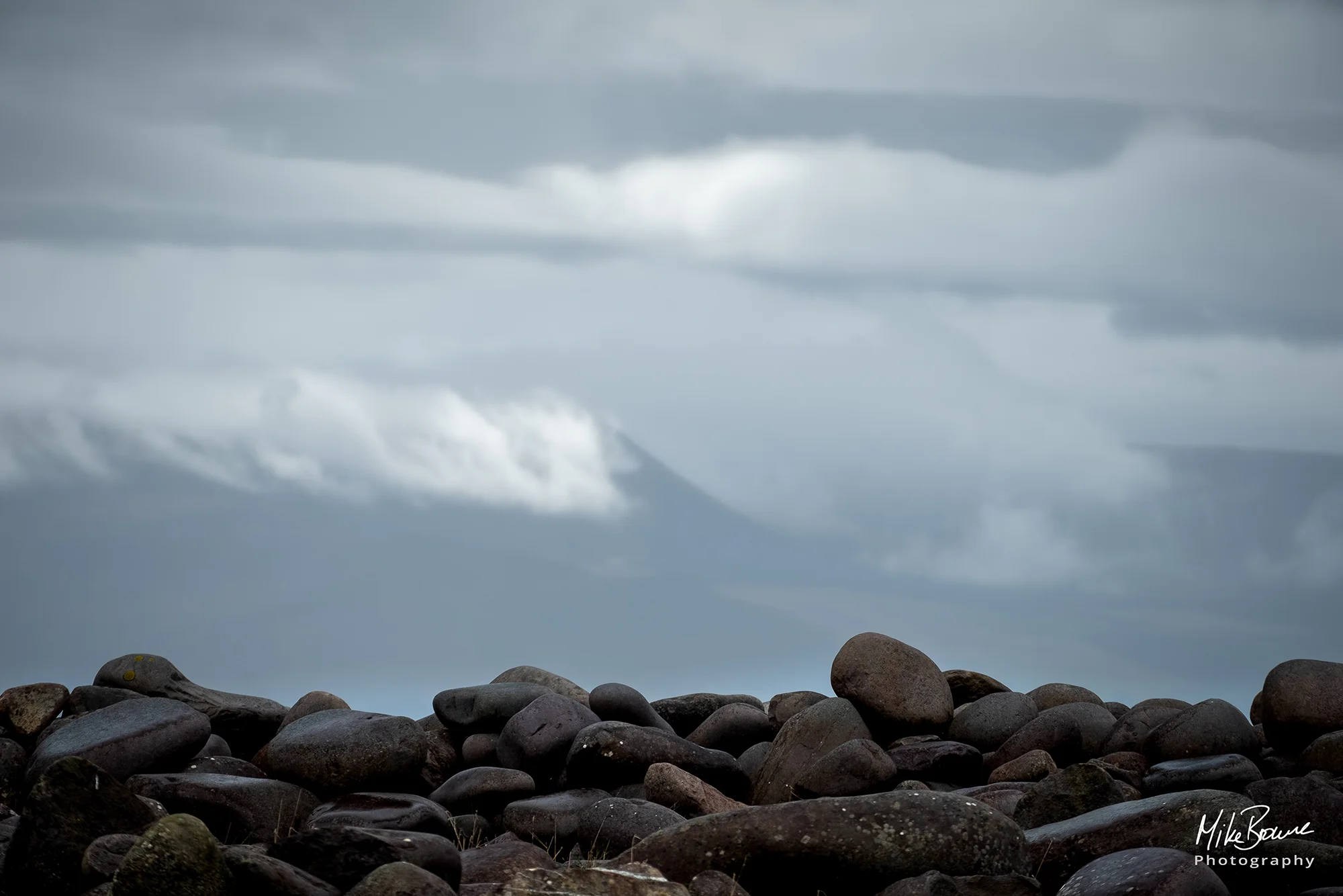 Rocks in foreground with a hazy sky over distant hills beyond