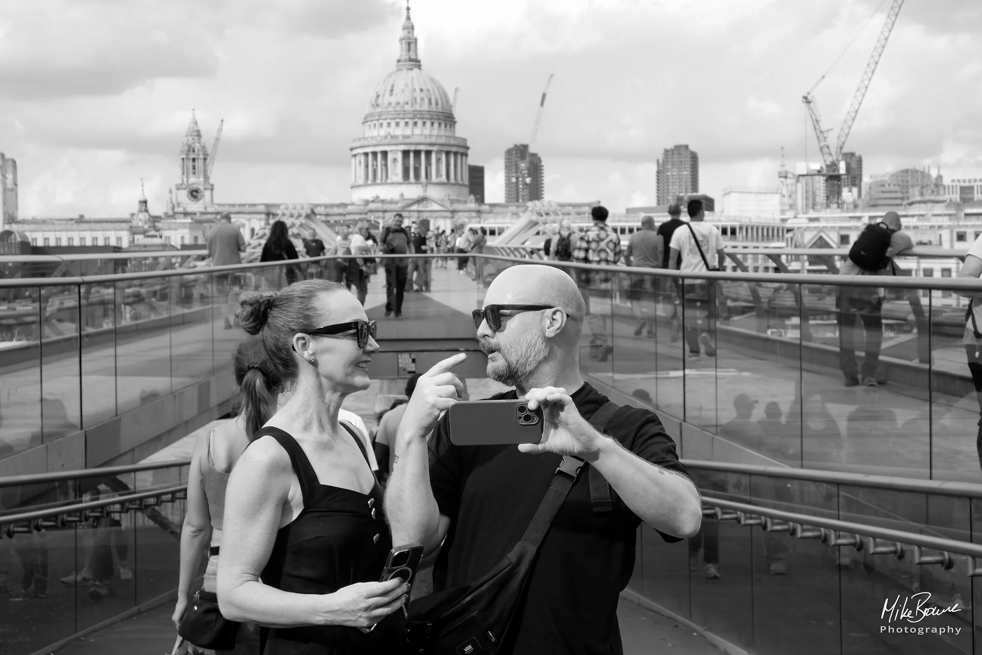 Man and woman about to take a selfie over Millennium Bridge with St Pauls cathedral