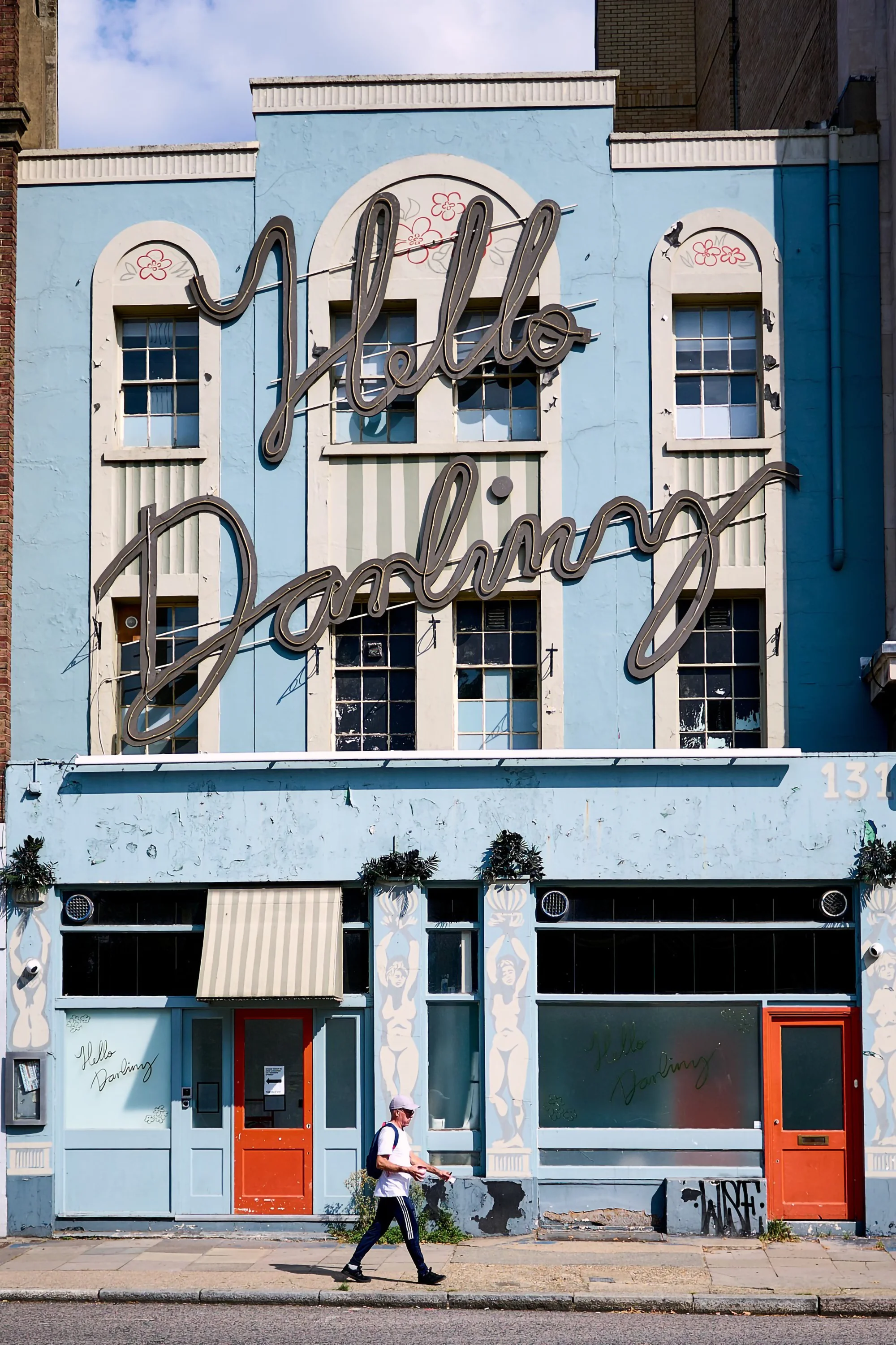 Woman walking past old blue and white restaurant in Central London