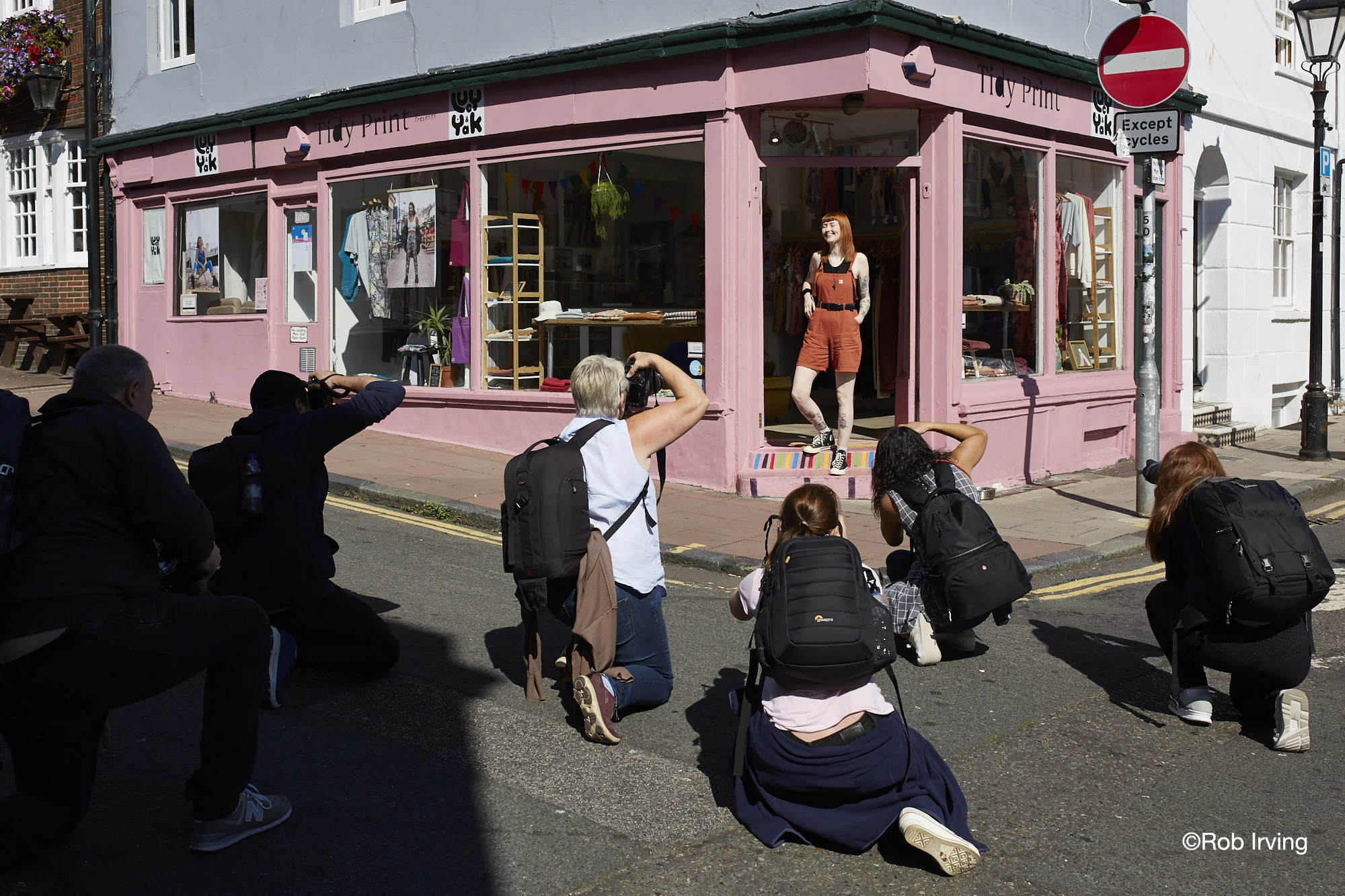 Woman standing in a shop doorway being photographed by a group of photographers