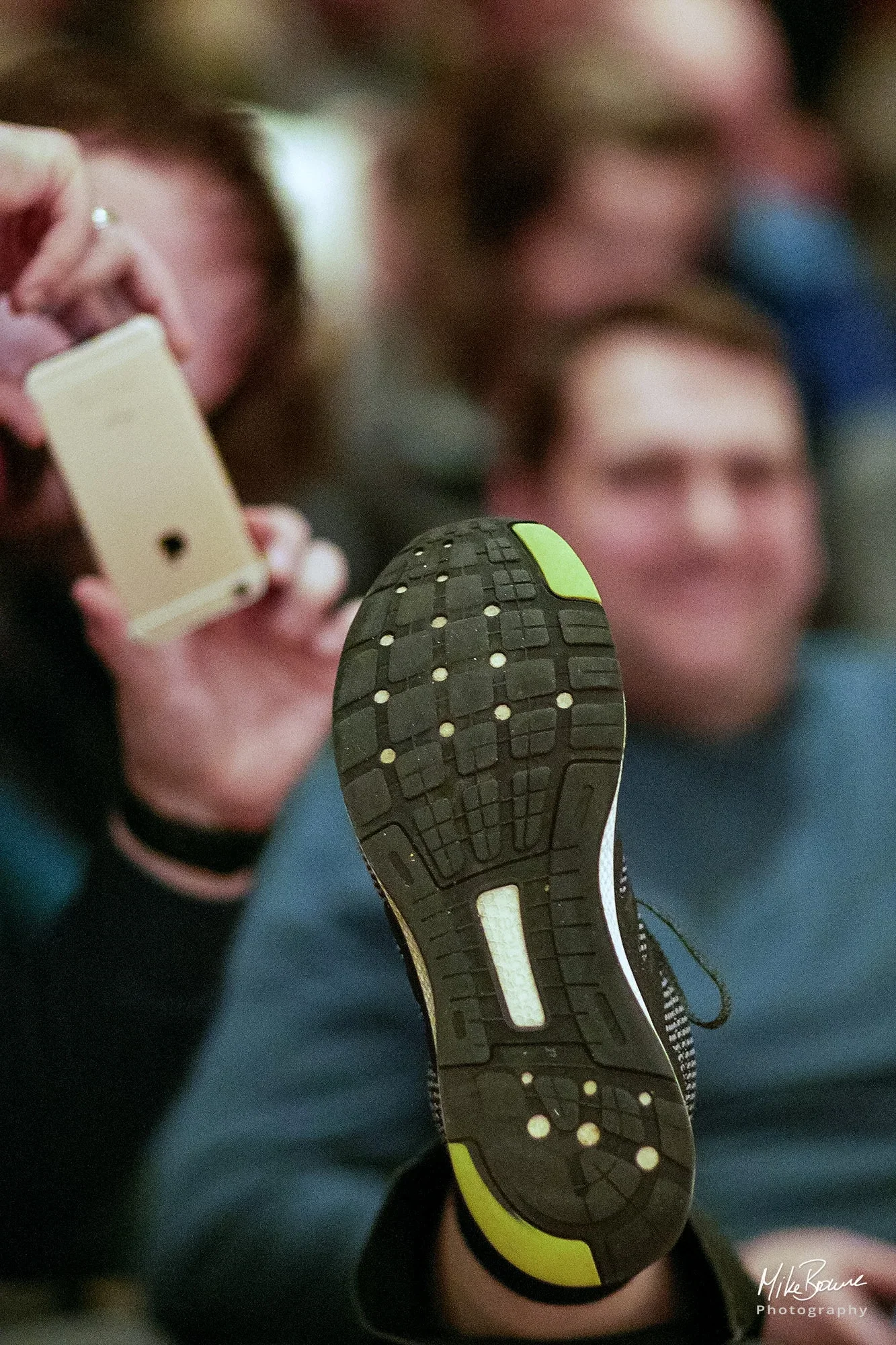 Man photographing another man\'s shoe with an iPhone