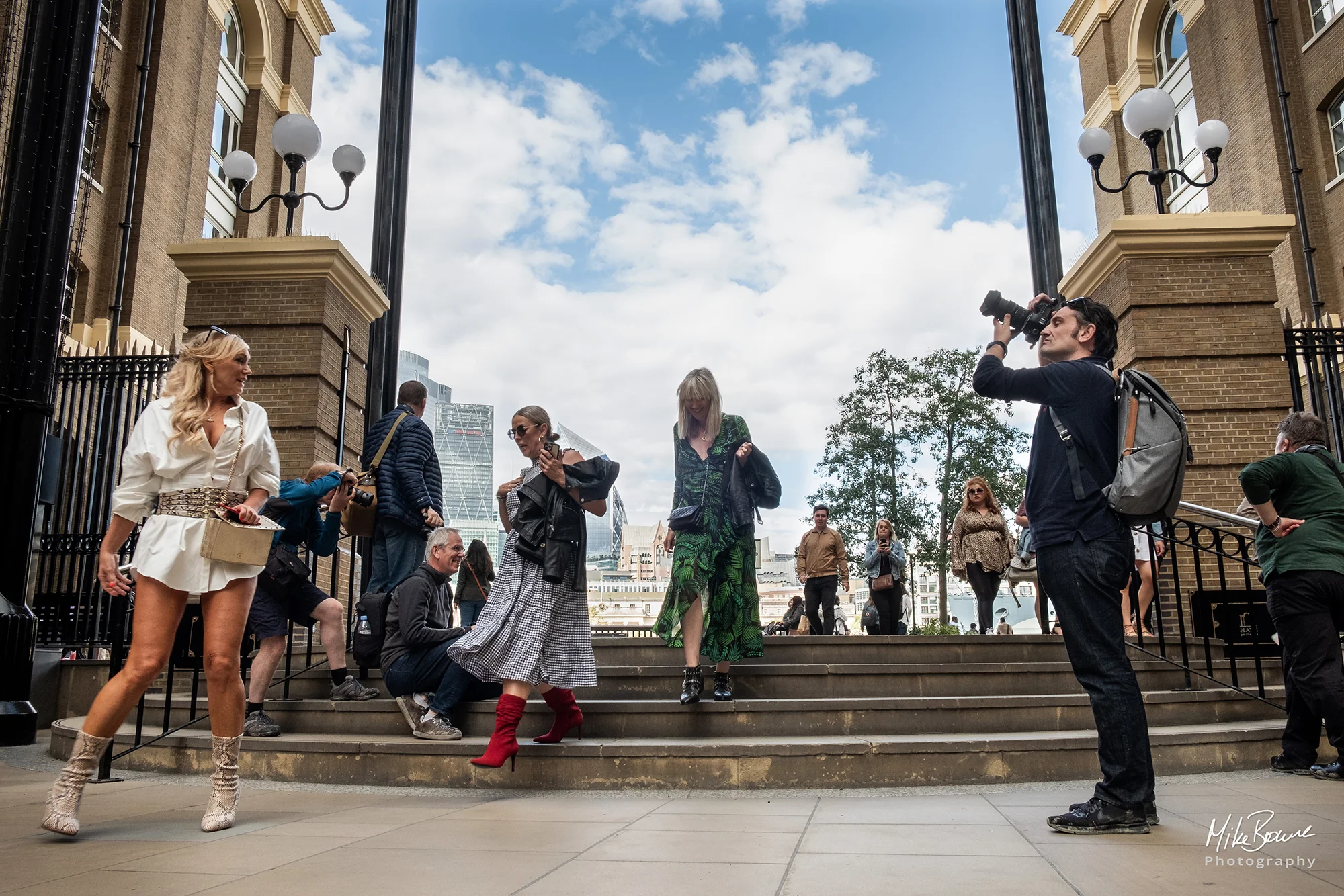 Funky young lady in short white shirt dress and a man using a camera opposite her on London street