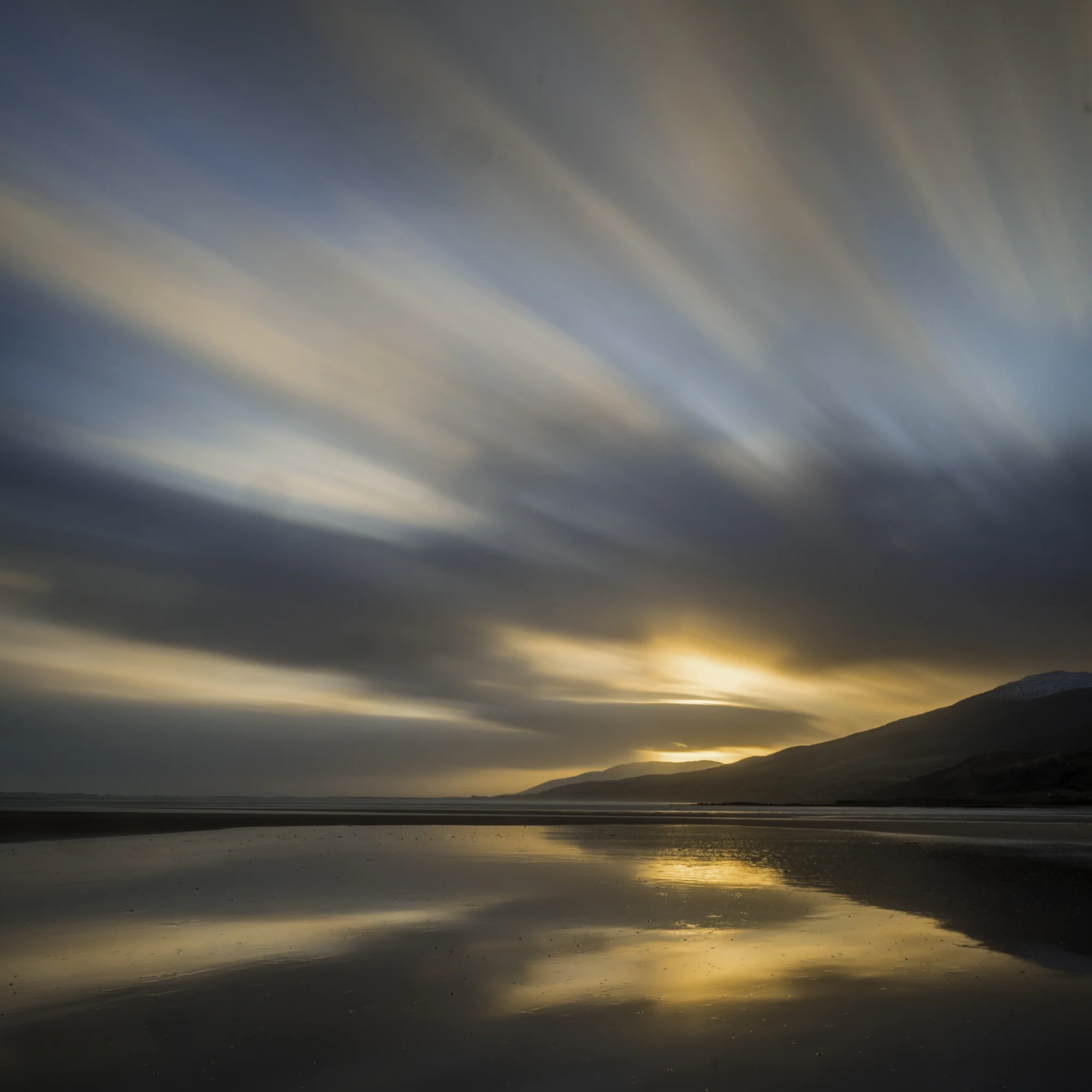 Streaking clouds and sunrise reflected in sea at dawn on Cappagh