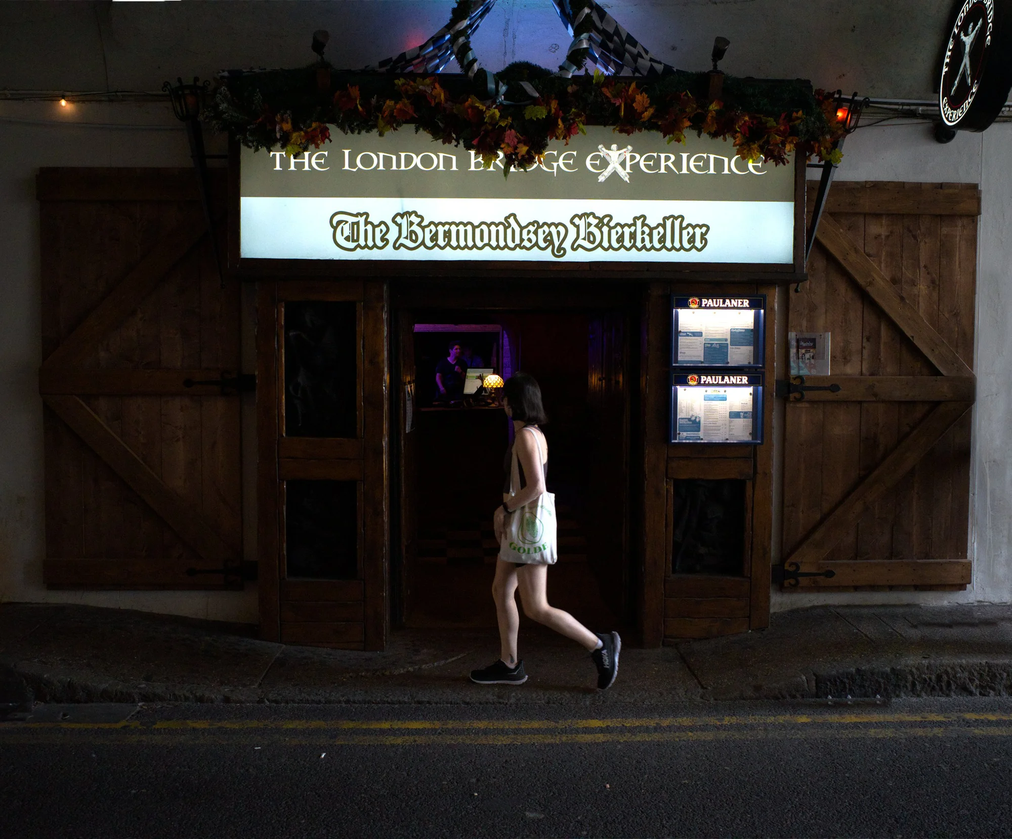 Young woman looking into doorway of the London Bridge Experience as she strides past