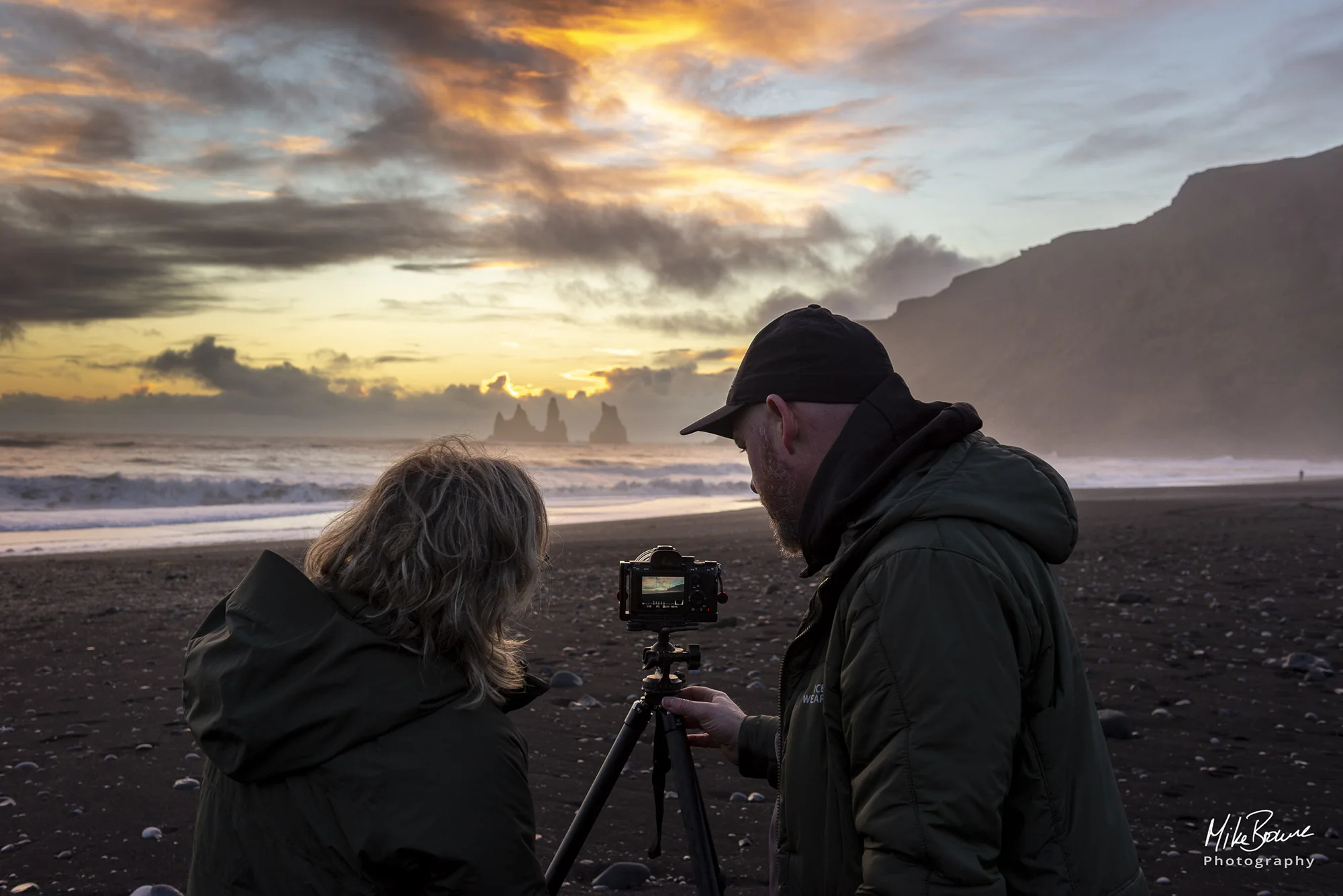 Female and male photographers photographing sunset at Sea Stacks in Vik Iceland