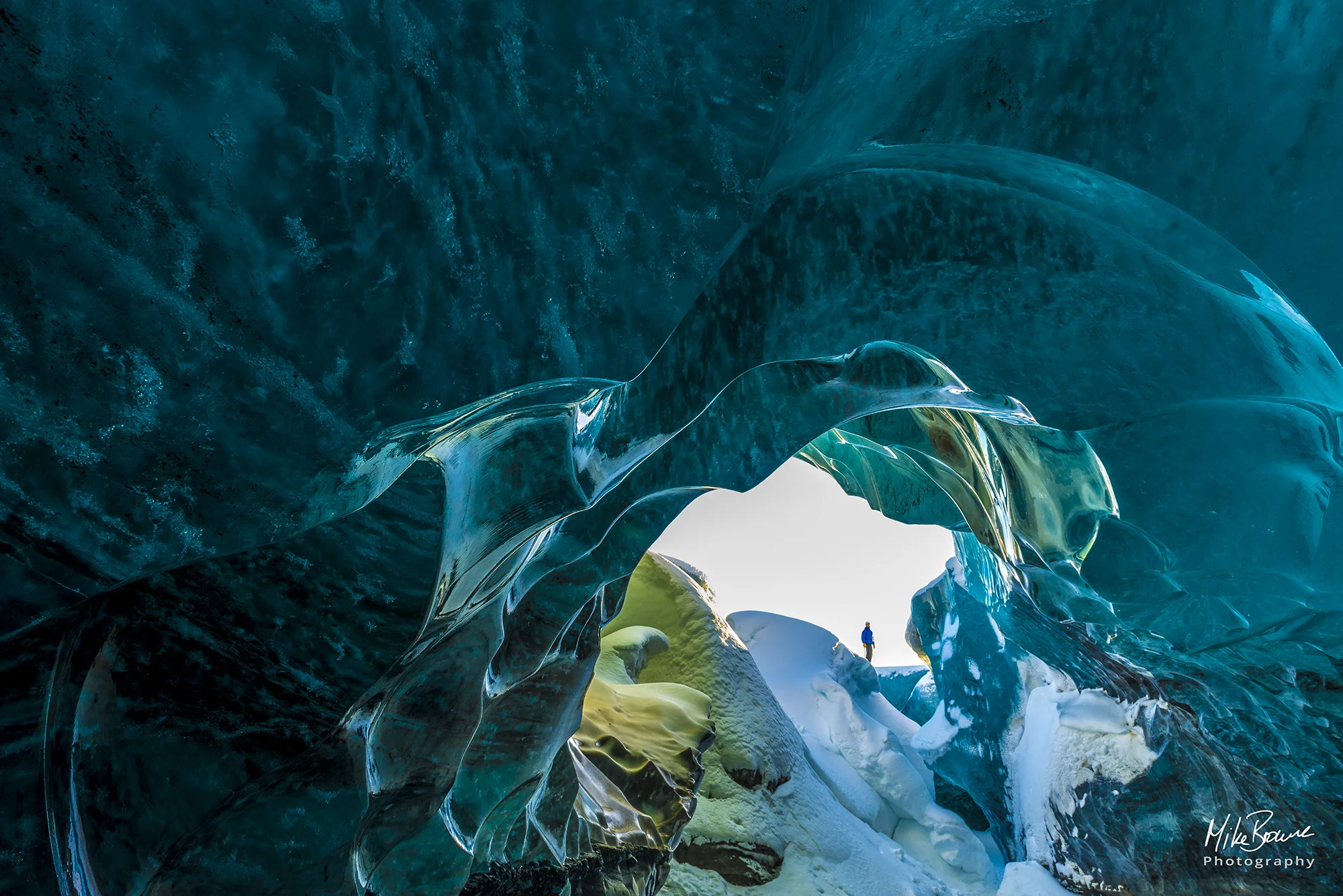 Man standing in entrance to an ice cave in vatnajokull national park Iceland