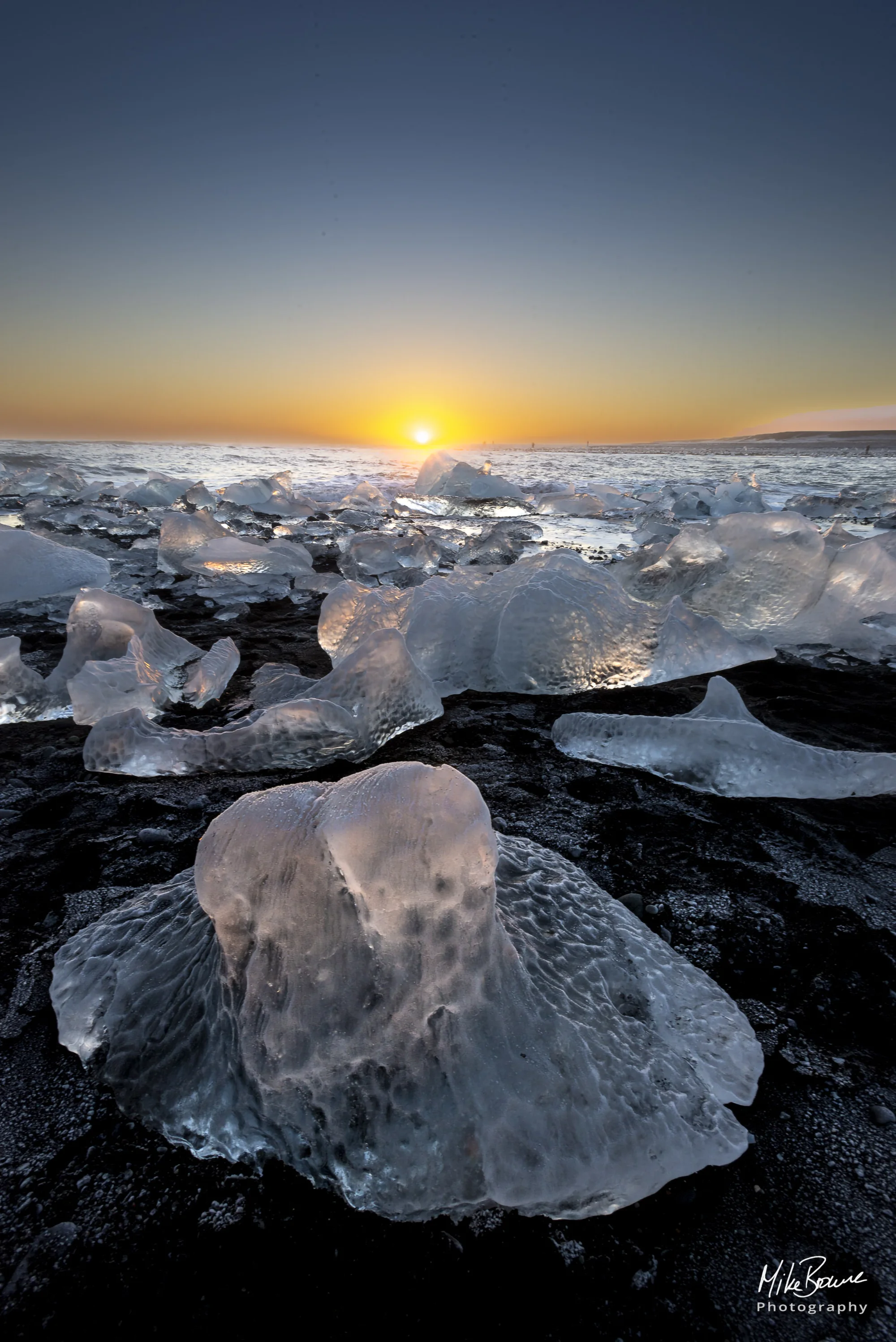 Sunset shining through ice bergs on black sand beach in vatnajokull national park