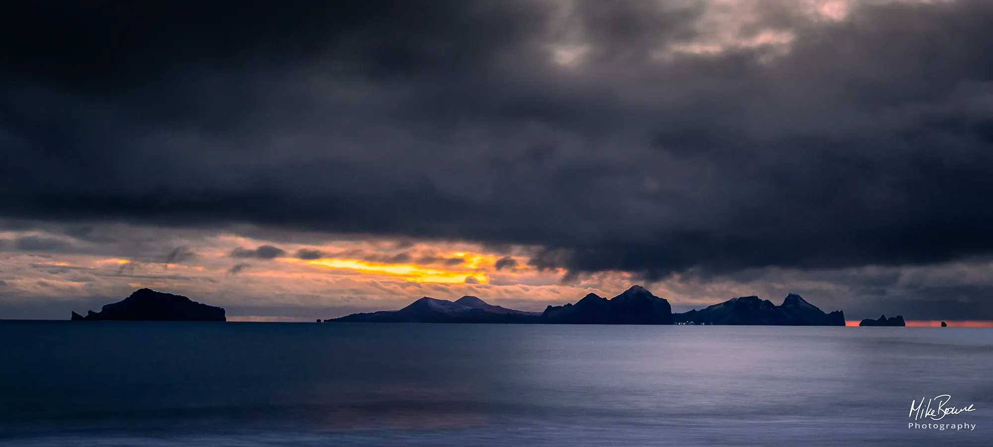 Orange sunset under storm clouds on beach in south Iceland