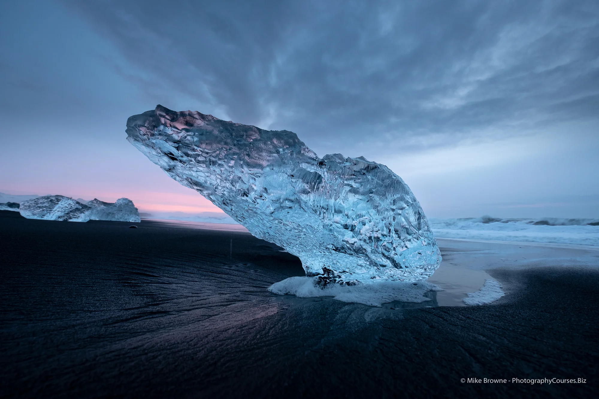 Iceberg on black beach with sunrise clouds at vatnajokull