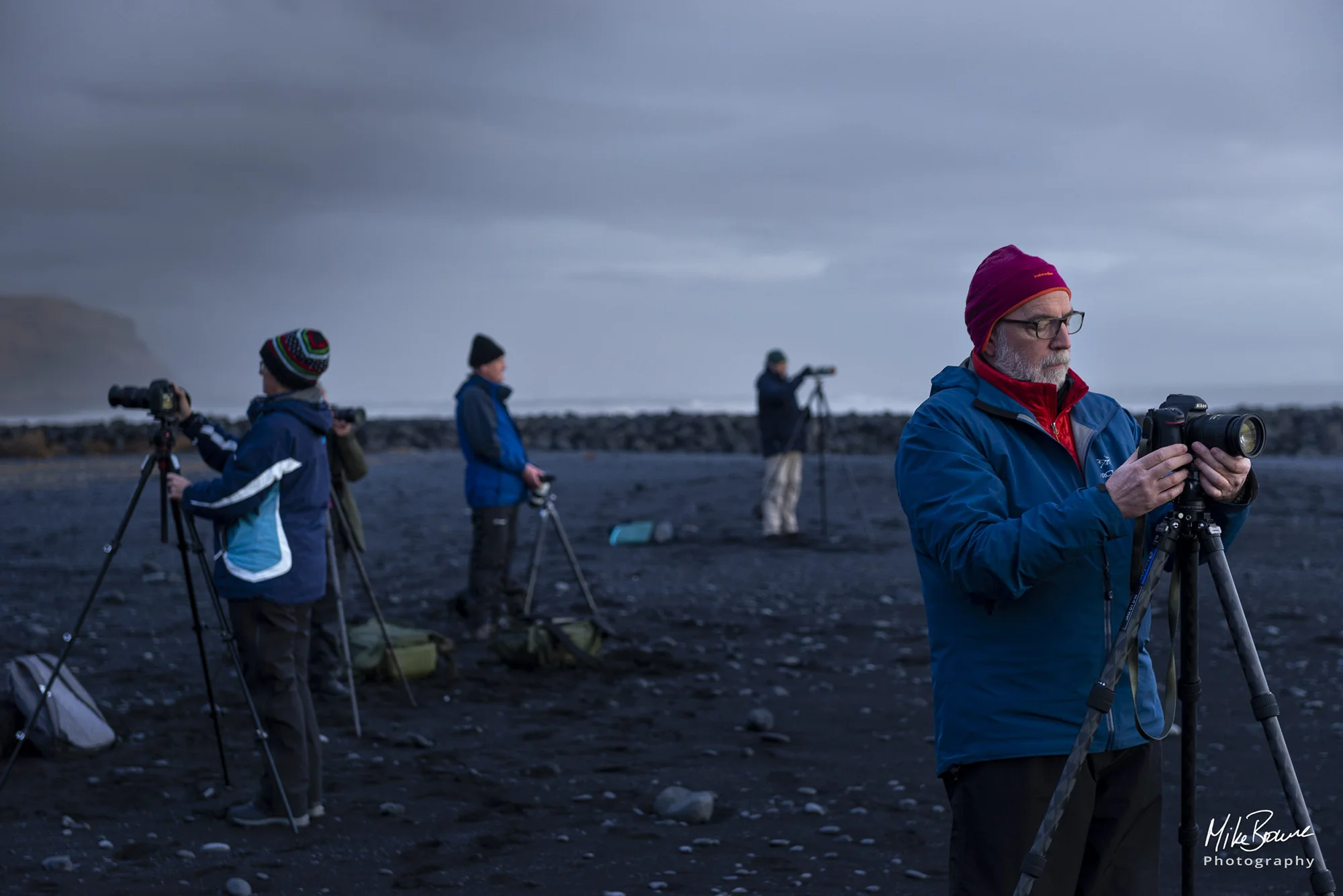 Four photographers prepare cameras at twilight in Iceland