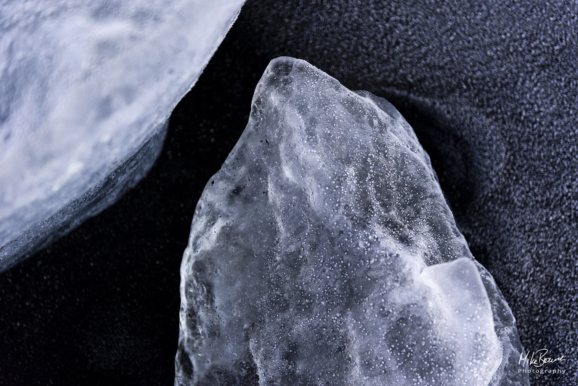 Frost covered ice laying on black sand