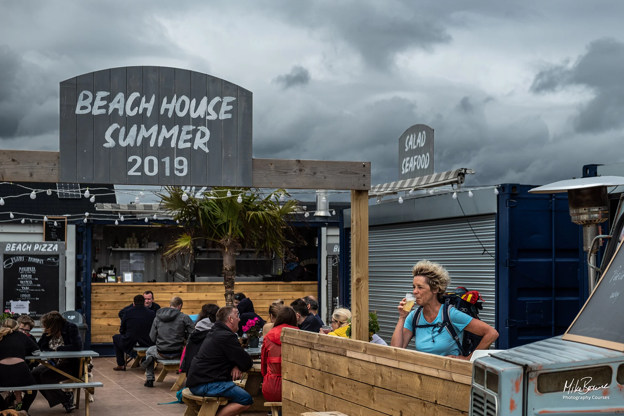 Woman enjoying a beer at a beach bar during a storm