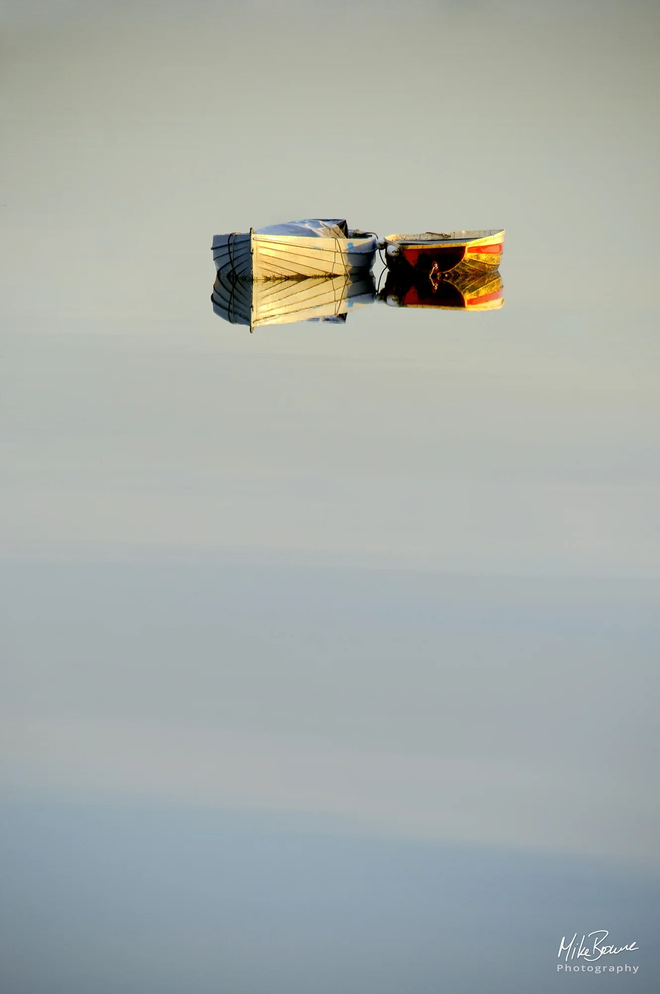 small boats at sunrise reflecting with sky in water