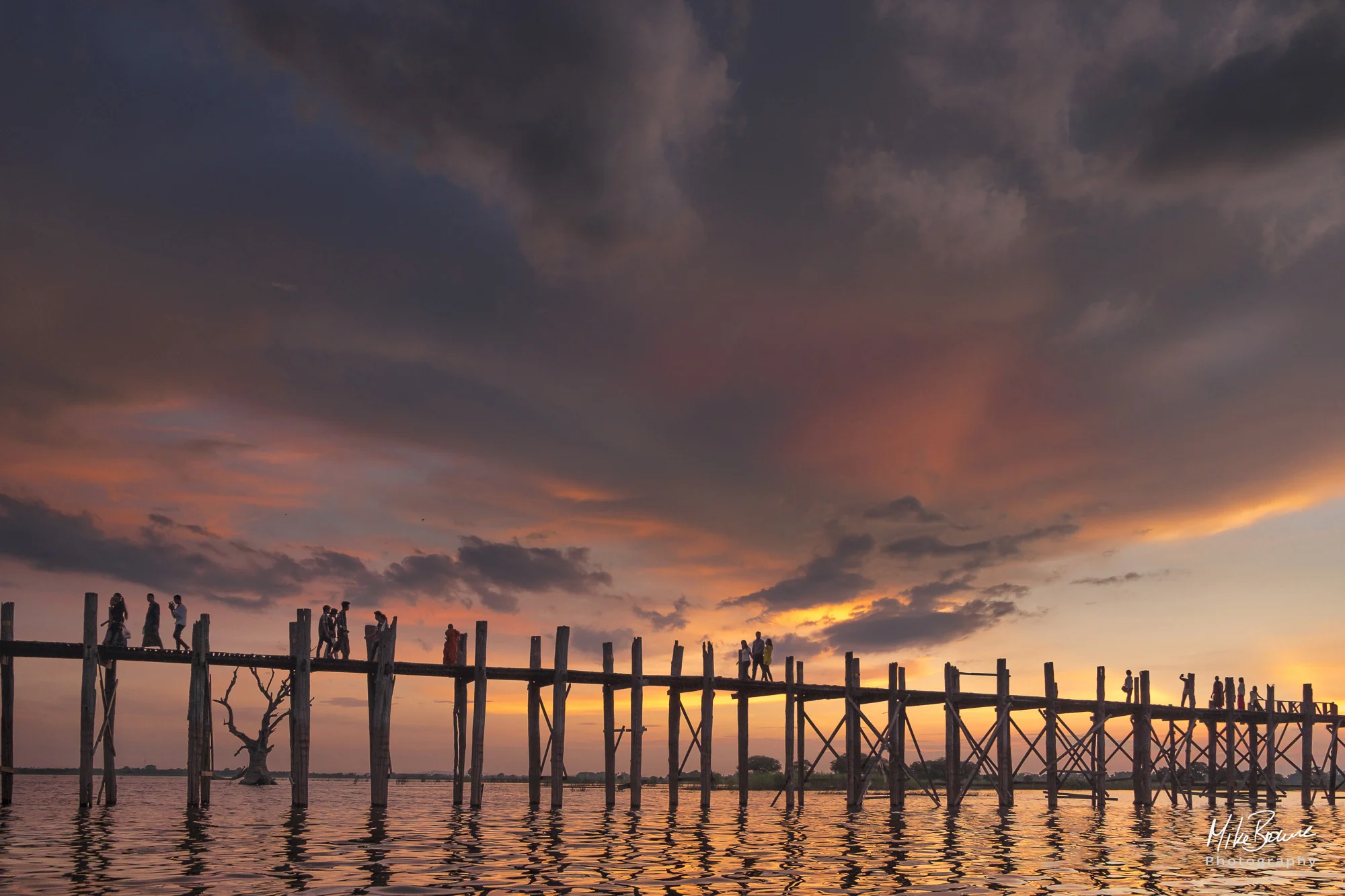 Tiny figures cross the Ubien Bridge in Mandalay at sunset