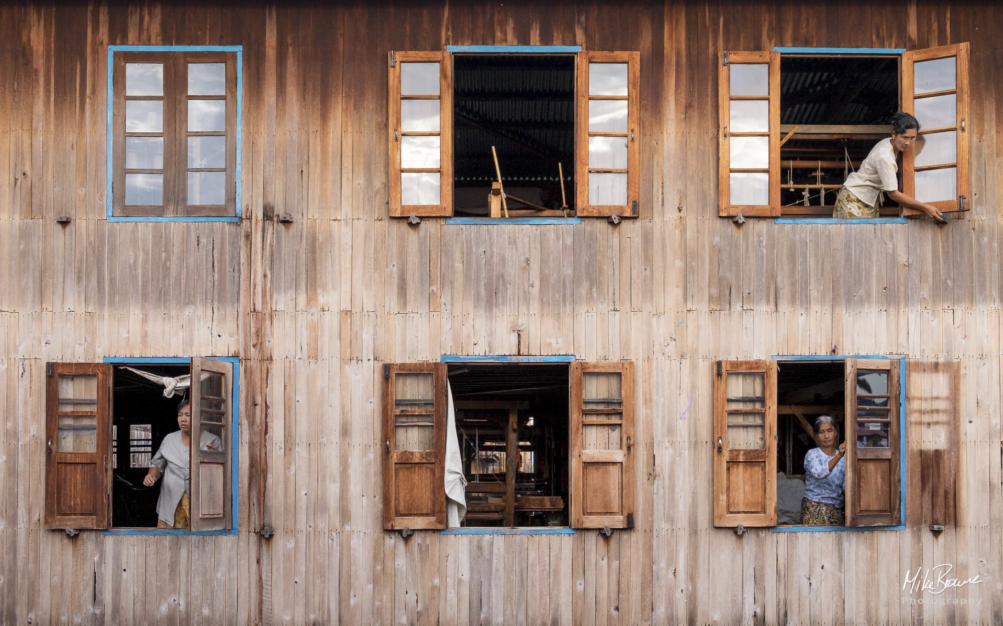 Three women closing six windows on a wooden house