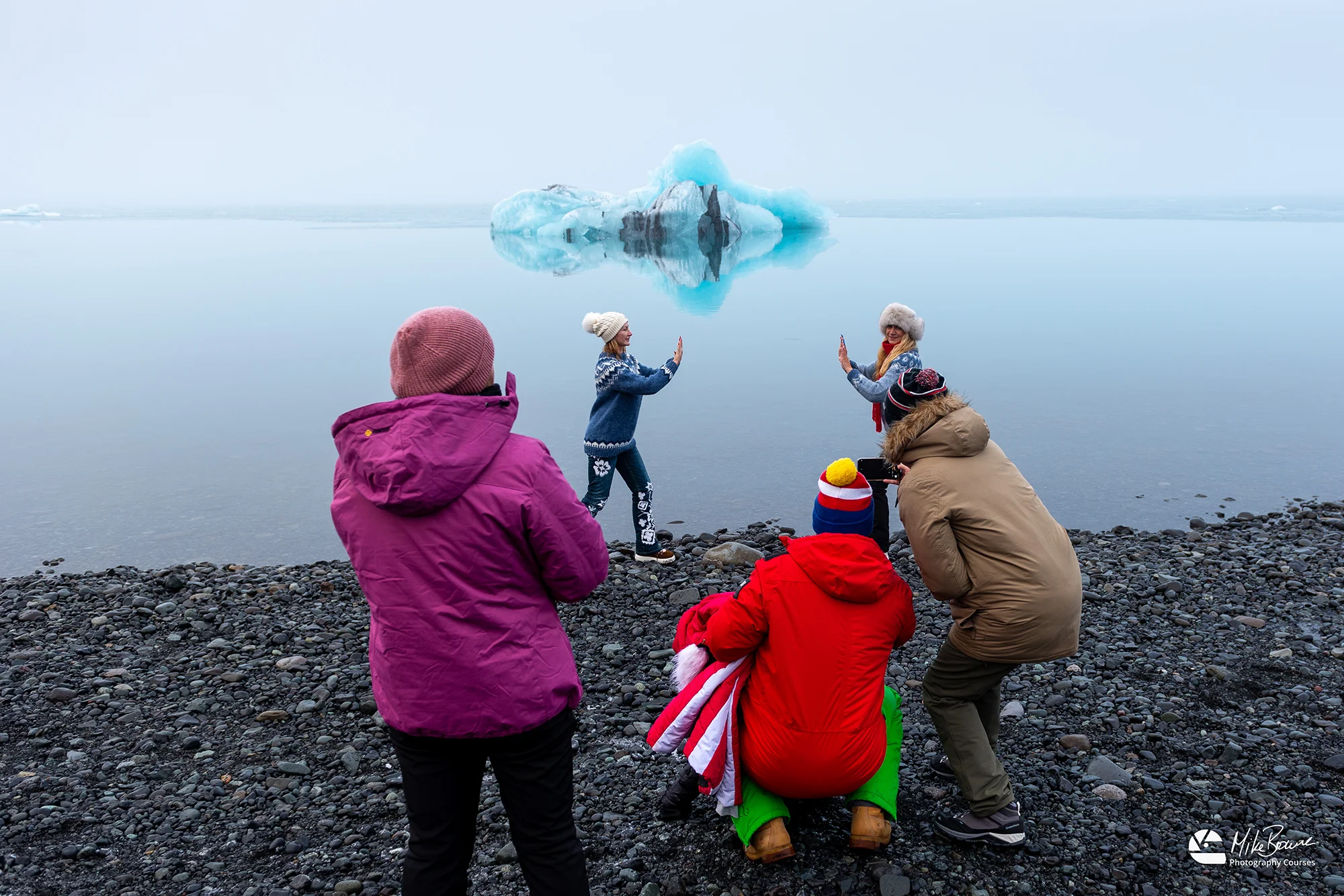 Tourists at Jökulsárlón Iceland pretend to hold a giant iceberg for a photo