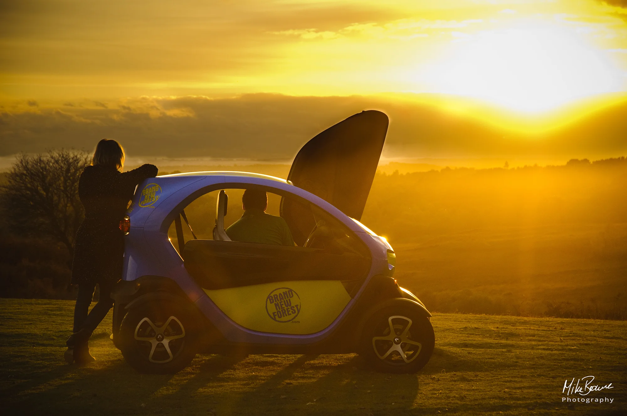 Man and woman admire sunset from their Renault Twizzy