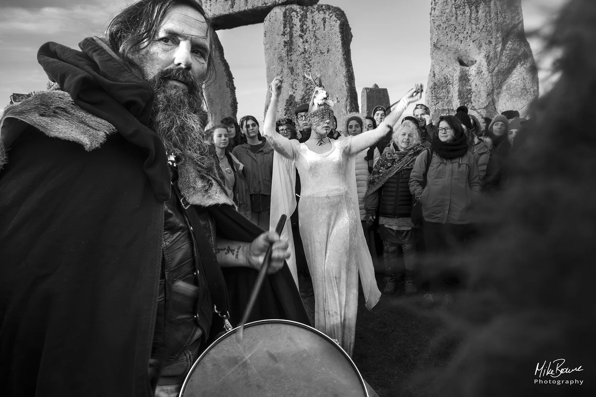 Man playing drum as girl in white dances at Stonehenge winter solstice