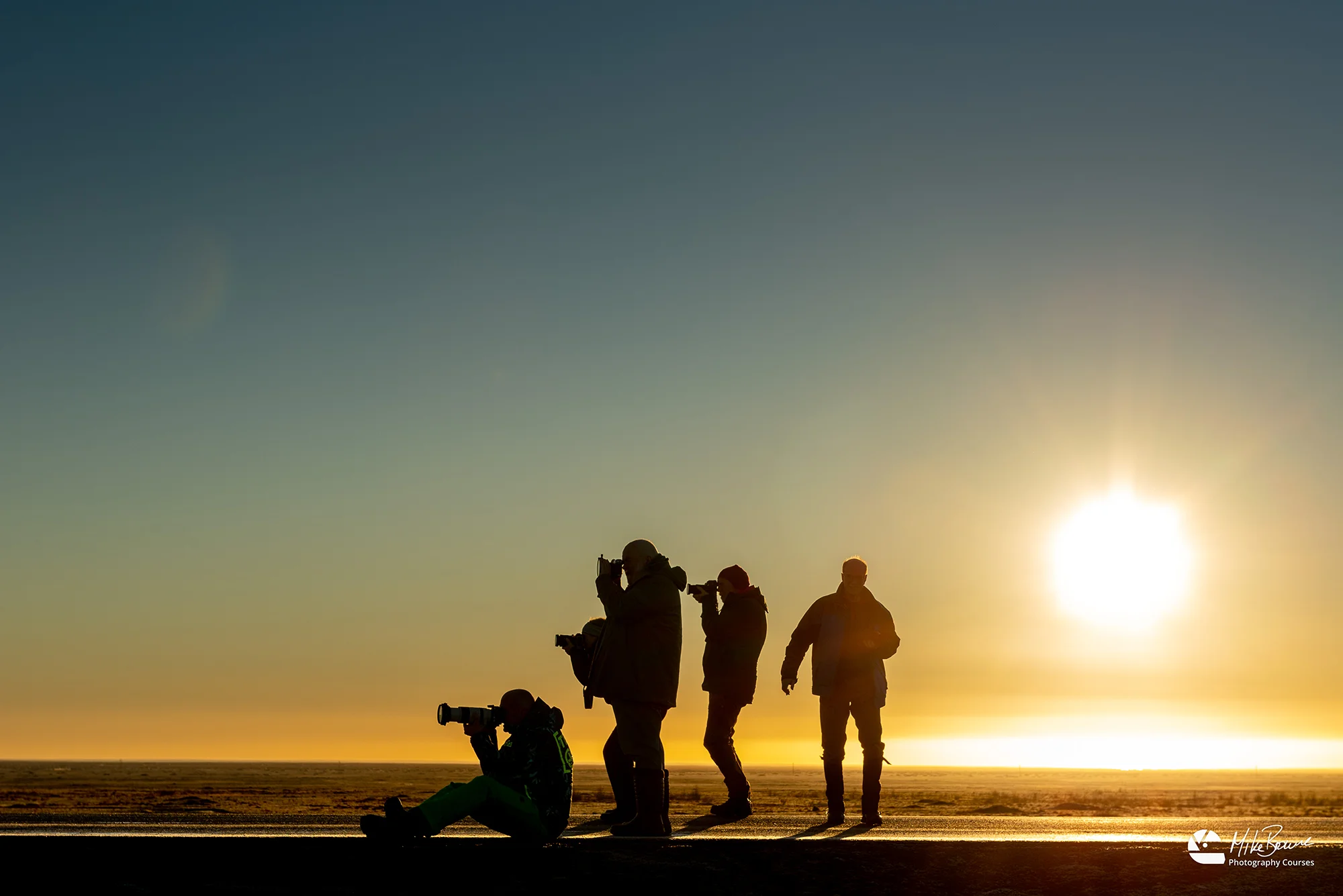 Five photographers with cameras raised standing in road at sunrise