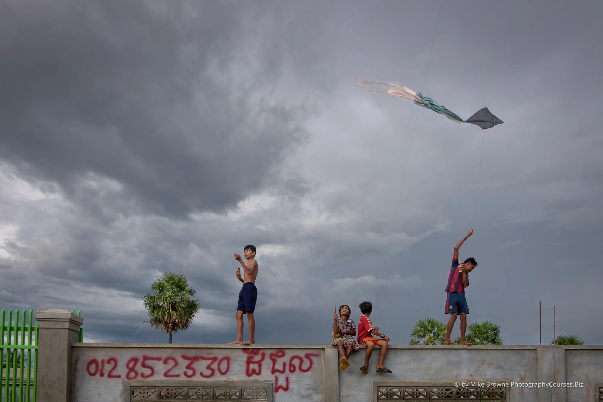 Children flying kits from top of a wall in Siem Reap, Cambodia