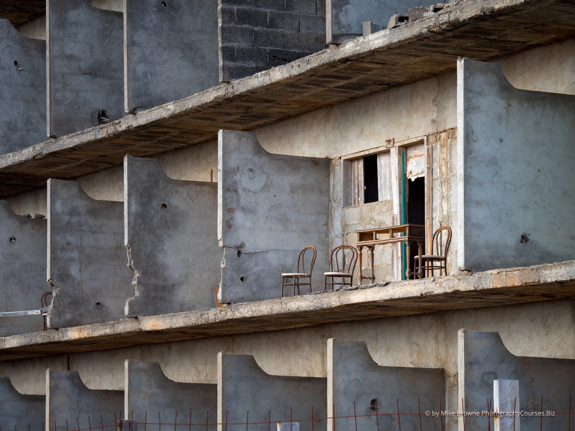 Three chairs and a table on the balcony of an abandoned hotel on Lanzarote