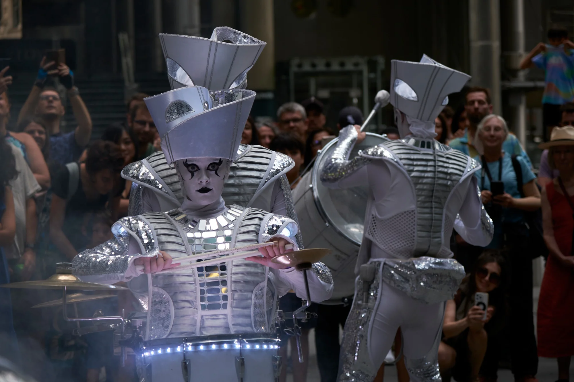 Drum majorettes in heavy black and white make up and dressed in silver and white performing on streets of London