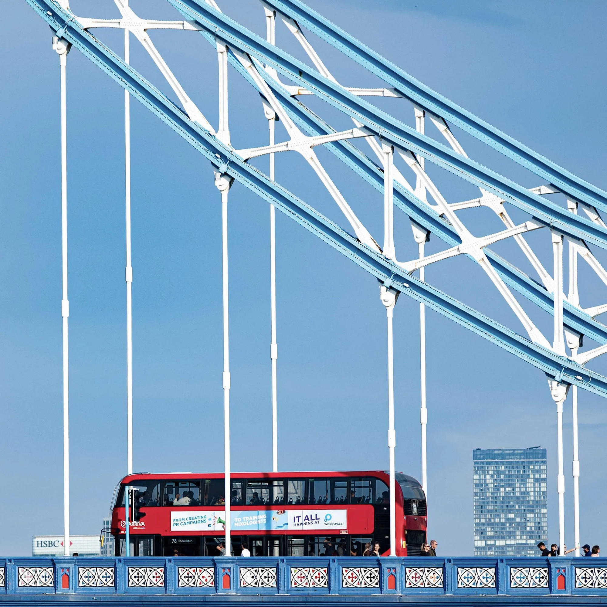 Red London bus crossing Tower Bridge in Central London on a bright sunny day