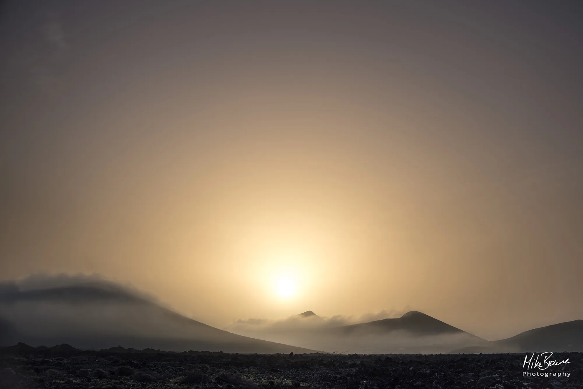 Hazy calima sunrise between volcanos near Conil, Lanzarote