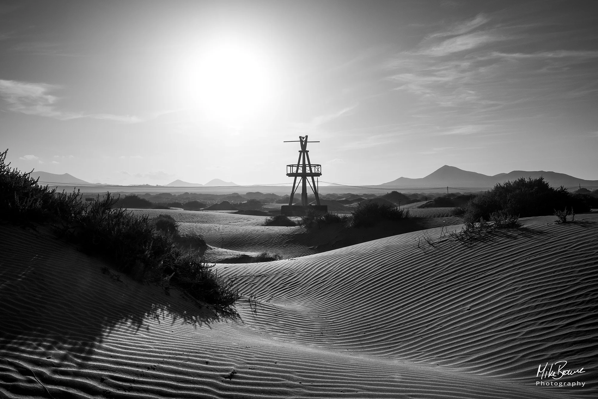 Windmill sculpture and rippled sand dunes on a bright sunny day