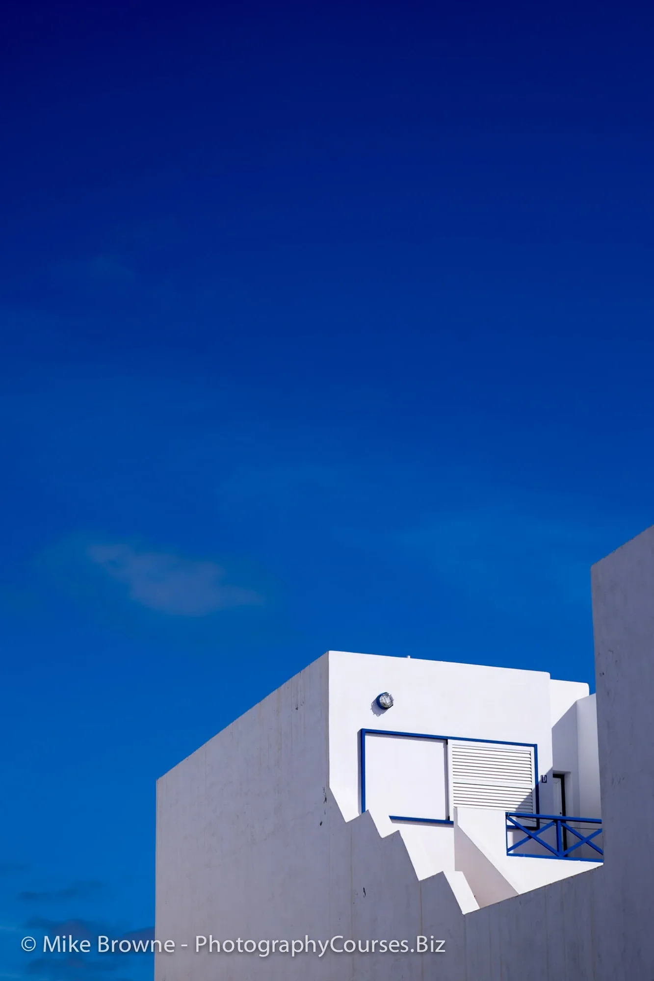 Corner of white Mediterranean house against clear blue sky