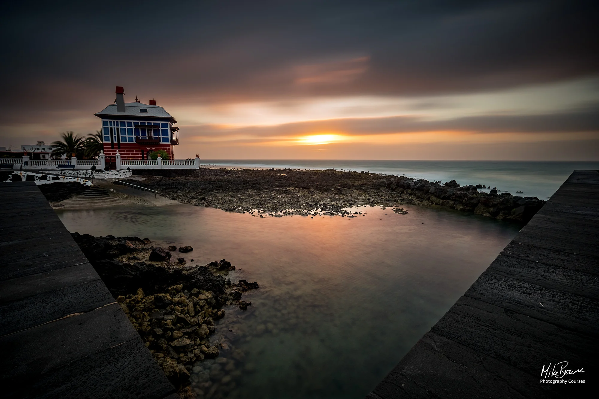 Lone house by the sea with storm clouds and sunrise above in Arrieta, Lanzarote