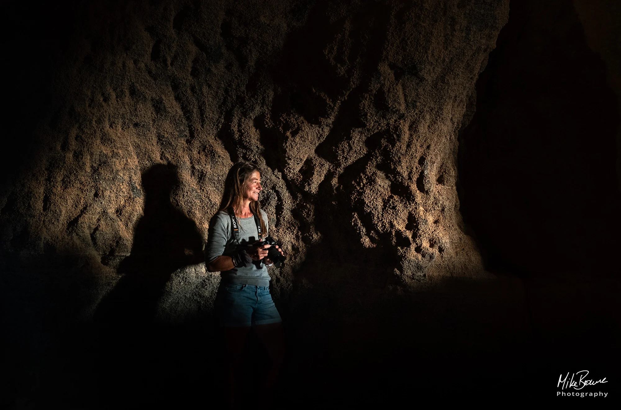 Female photographer in a cave holding a camera at Las Nieves, Lanzarote