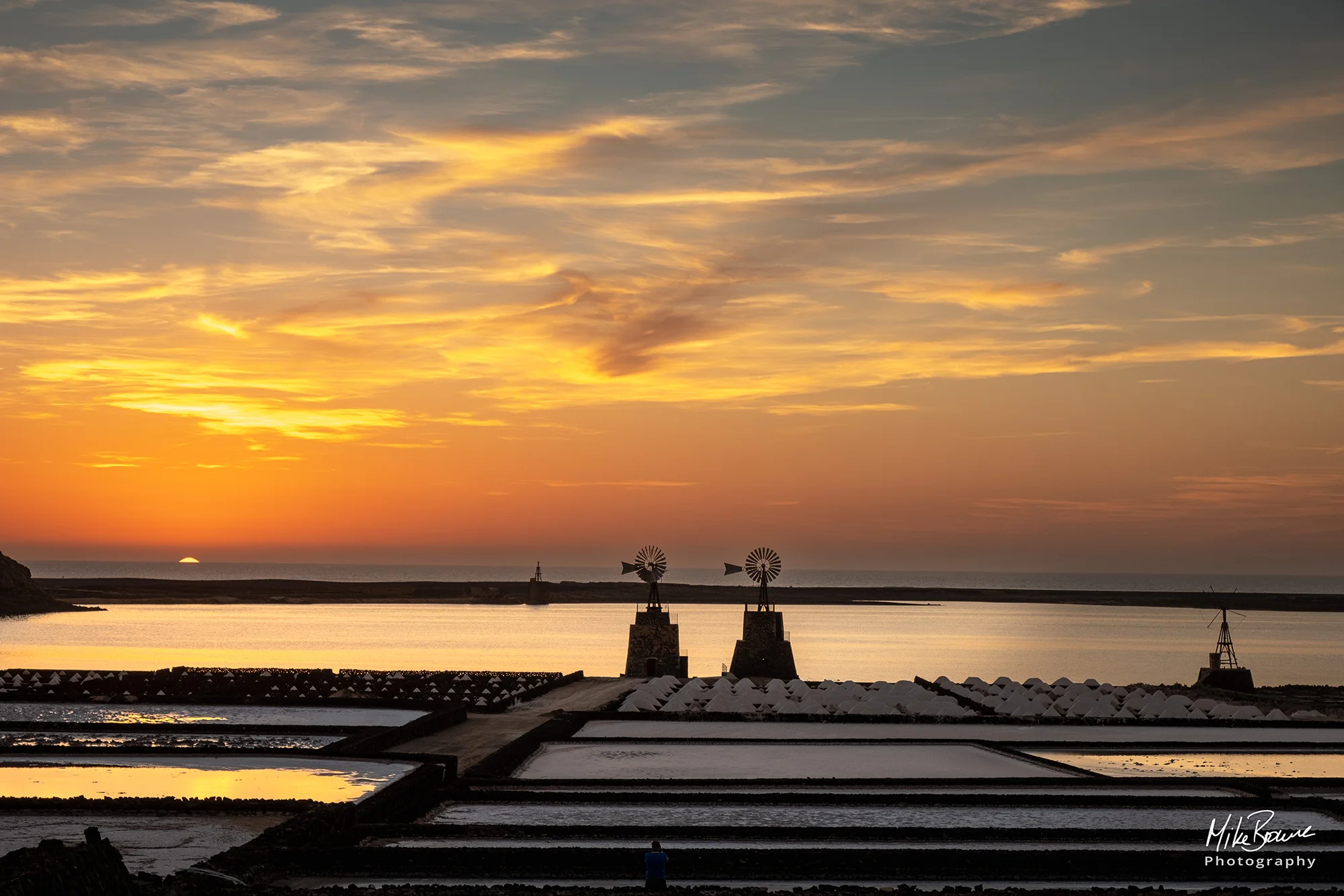 Sunset over the ocean and abandoned windmills and salt pans at sunset at Salinas de Janubio, Lanzarote