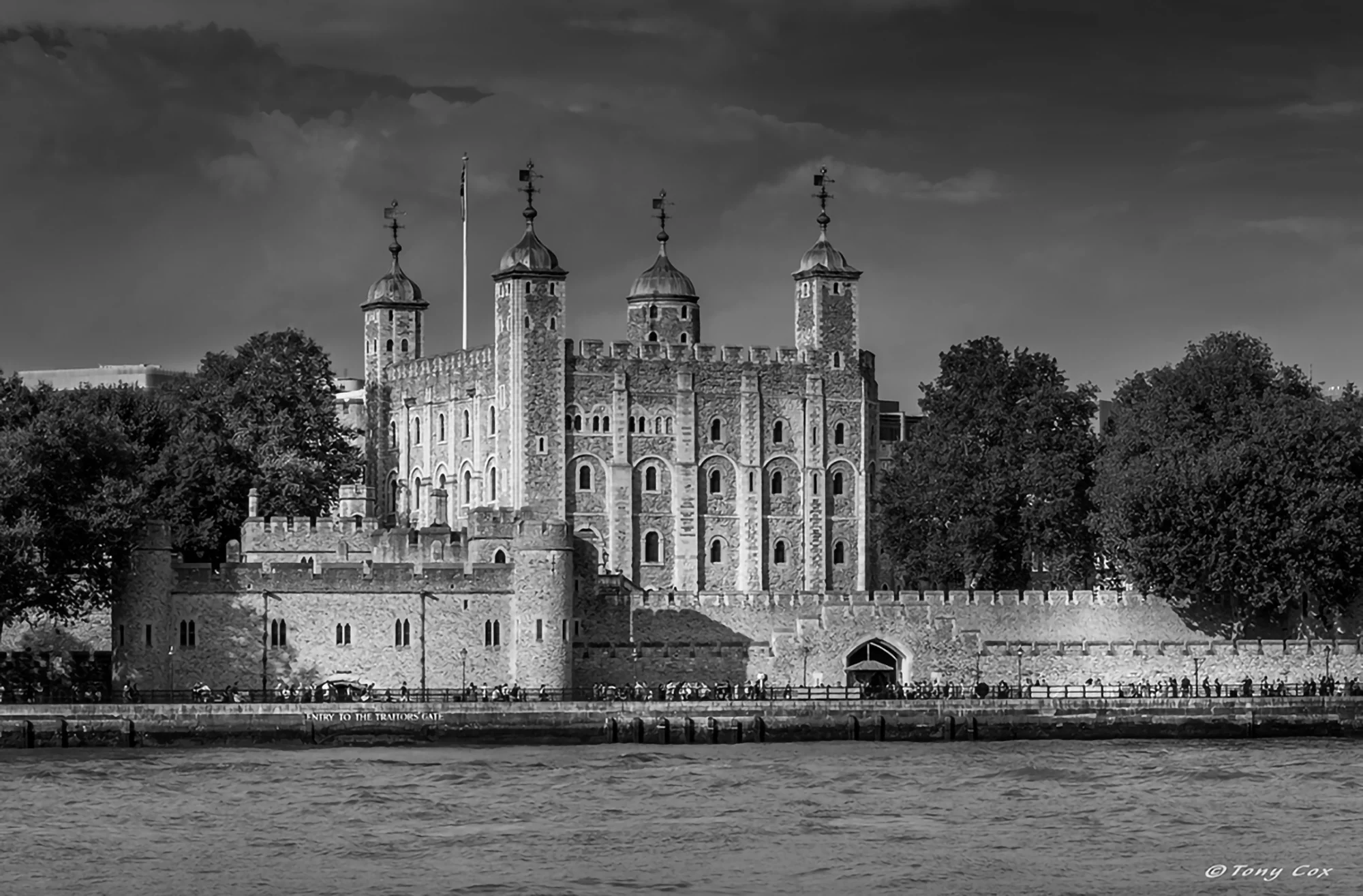 The Tower of London with many people walking past along the South bank