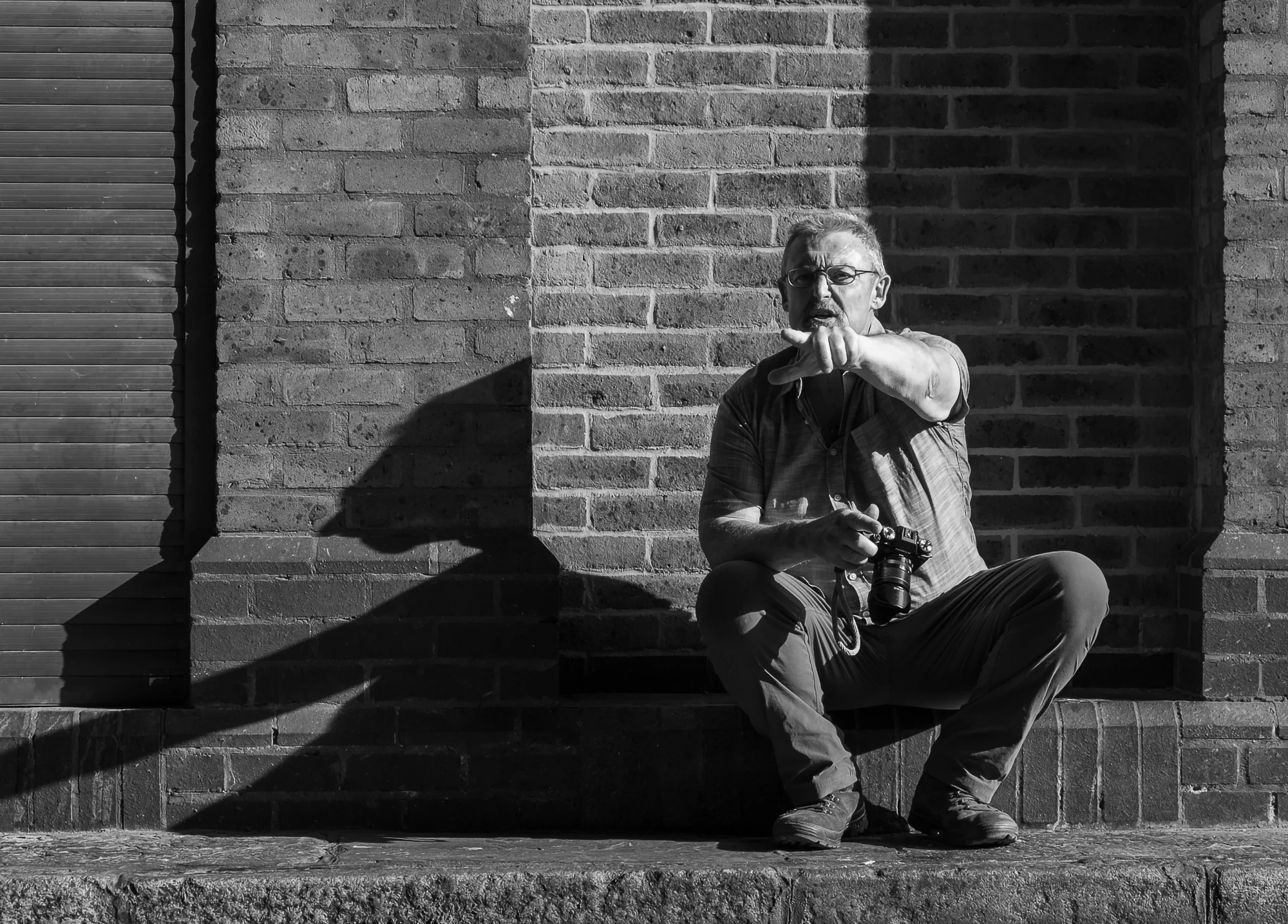 Photographer Mike Browne sitting on a step holding a camera and pointing