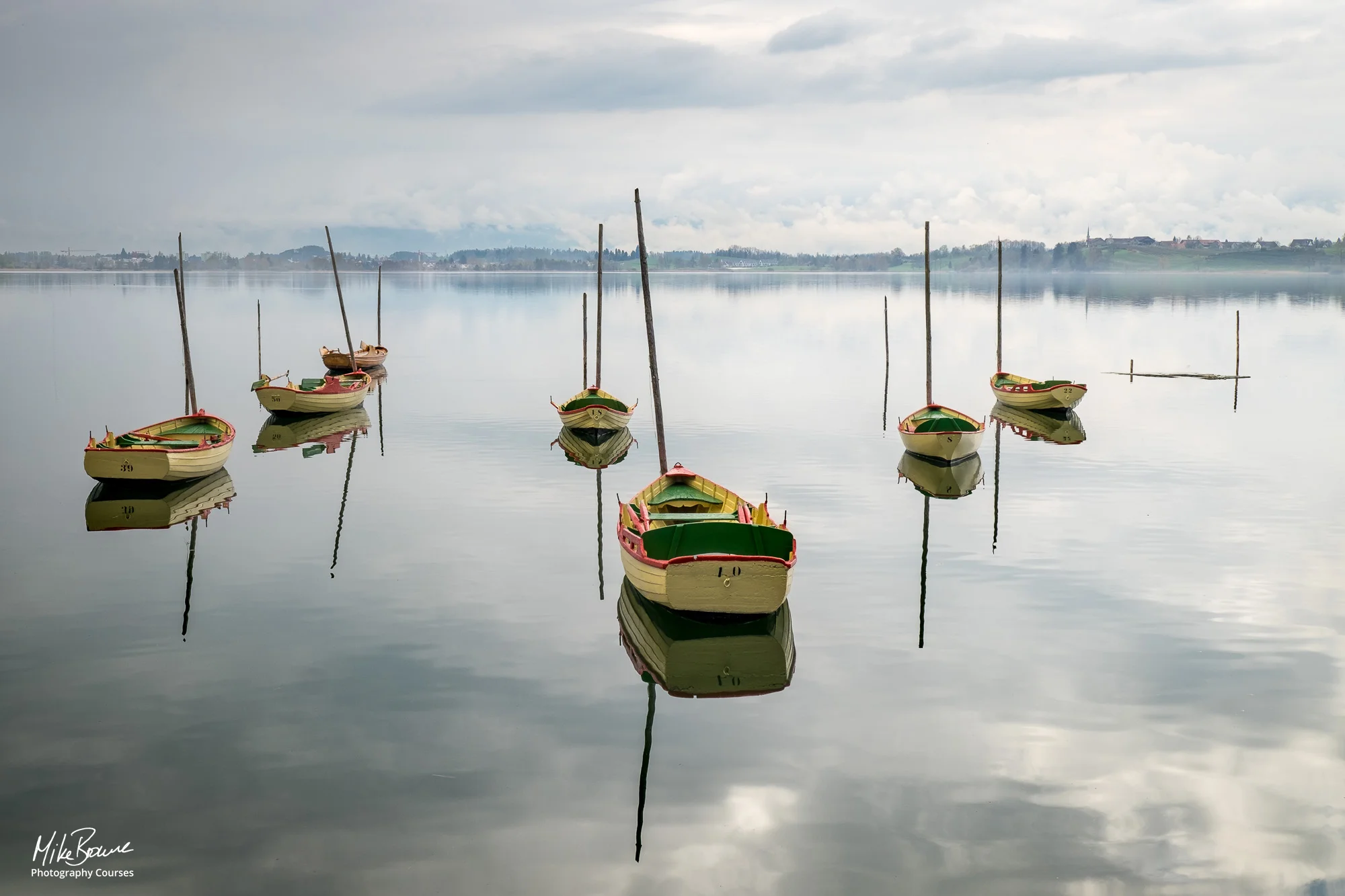Yellow boats on calm lake with misty sky and mountains beyond