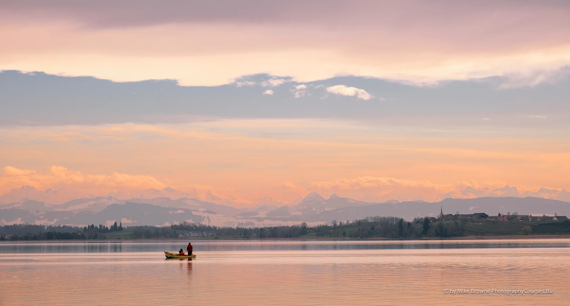 small boat on lake Pfäffikersee with red sky and distant mountains